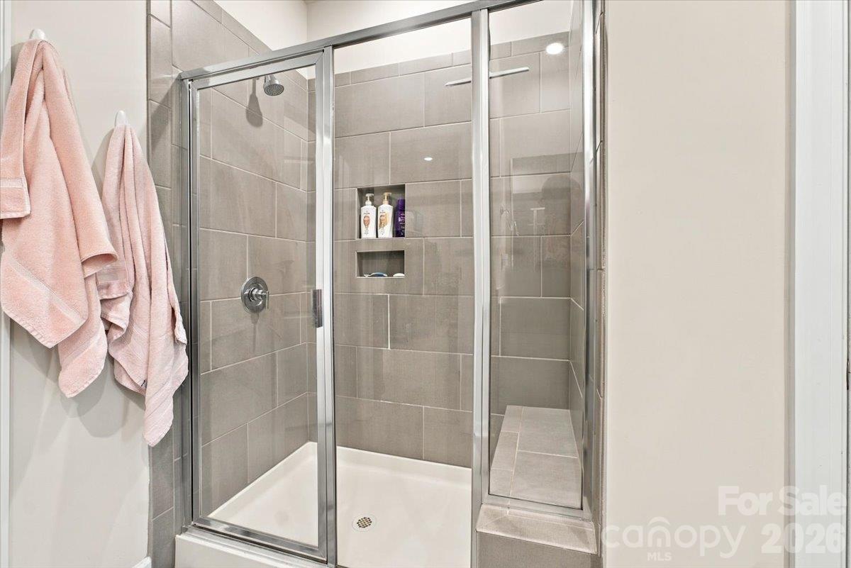 Primary tile shower features a bench for relaxing. - 7722 Porrera Street, Charlotte
