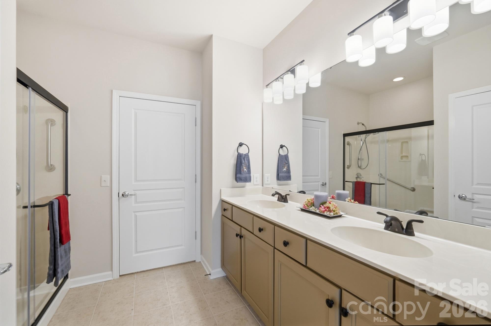 Primary Bathroom has lots of vanity space, double sinks, large shower with permanent seat, grab bars and a new shower glass door - 2047 Sweetleaf Drive, Indian Land