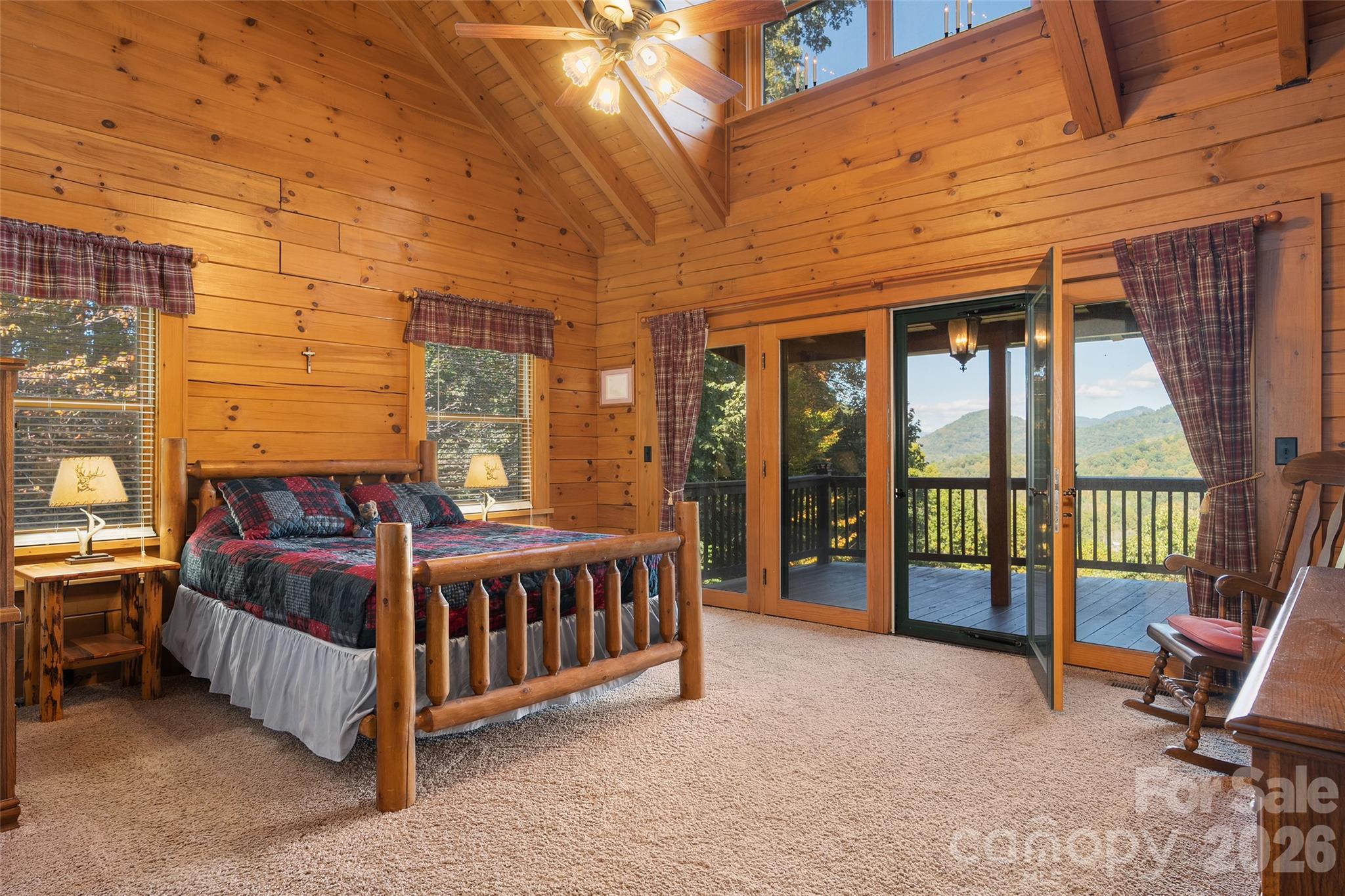 Spacious primary bedroom with warm wood finishes and access to the deck. - 124 Borges Lane, Waynesville