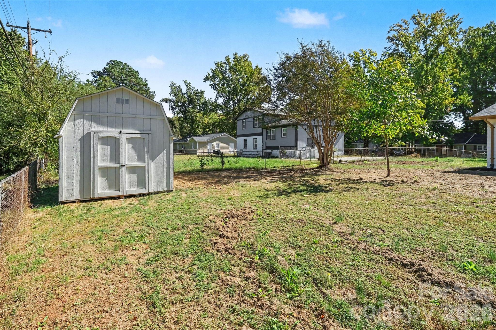 Large, open backyard complete with an exterior storage shed ideal for a lawnmower and tools, offering plenty of green space and mature trees. - 3801 Hillock Court, Charlotte