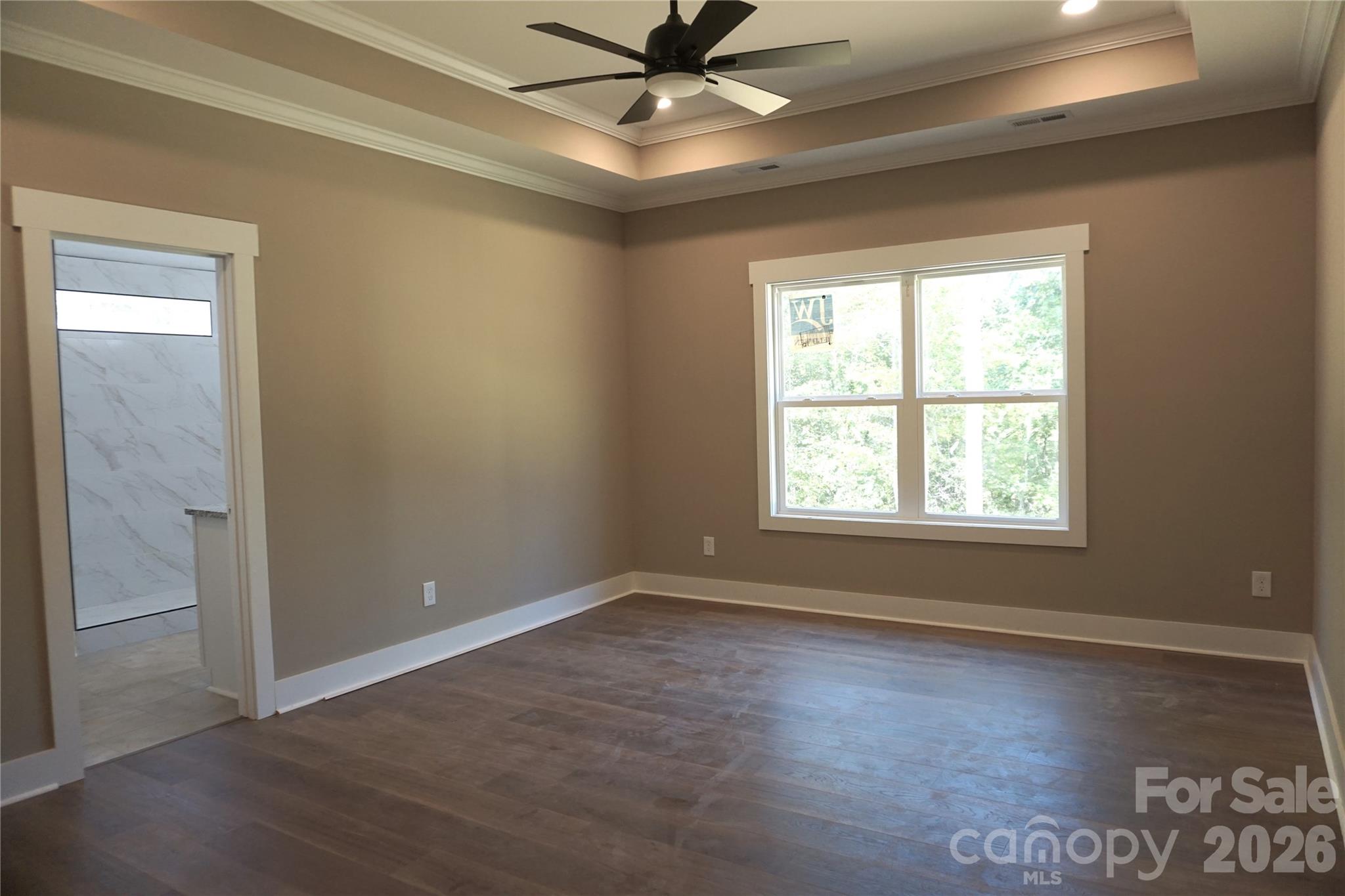 Primary Bedroom with tray ceiling overlooks the back yard. - 989 Rhyne Road, Clover