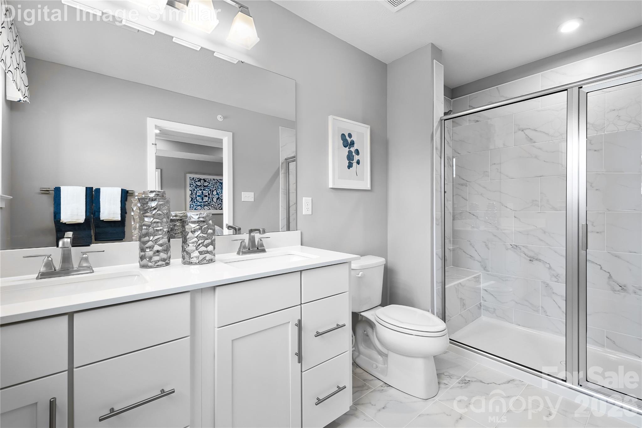 Private ensuite bath featuring optional sleek framed shower door, dual sinks with elegant fixtures, and built-in cabinetry for stylish, functional storage—your personal spa retreat. - 11204 Emerson Landing Drive, Charlotte