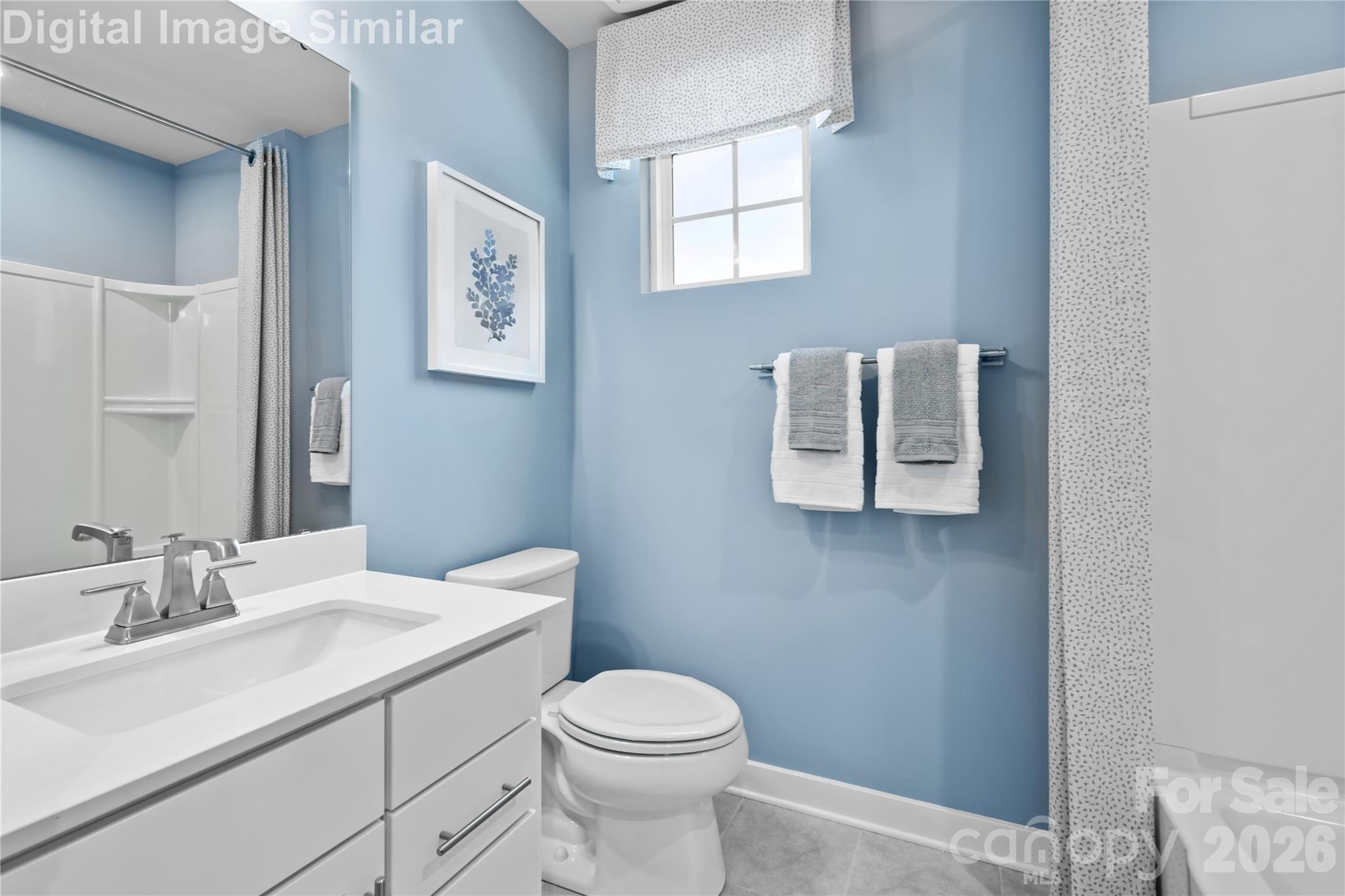 Bright shared bathroom with a sunlit window, full-size tub, and a large mirror—blending function and style for everyday comfort. - 11204 Emerson Landing Drive, Charlotte