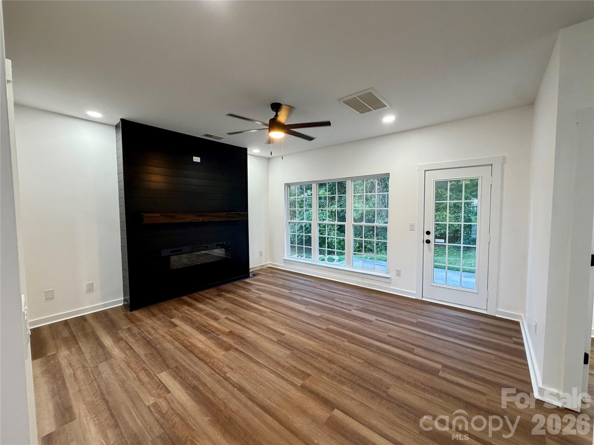 Den with Built in Black Fireplace in Wall. NEW LVP Flooring on main level. Doors opens to outside patio. - 116 Huckleberry Lane, Mount Holly