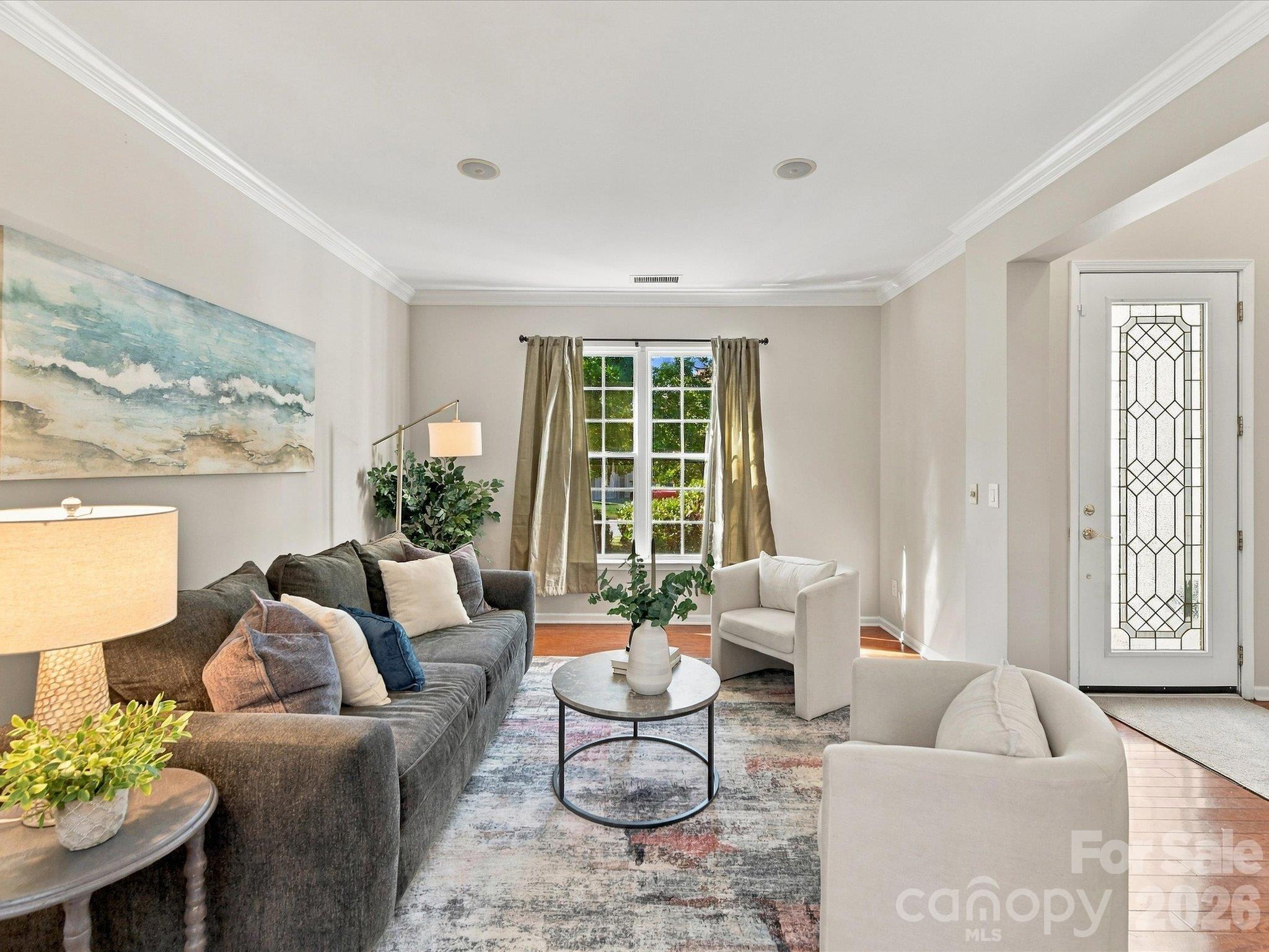 Spacious formal living room featuring rich hardwood floors, elegant crown molding, and an open layout that flows seamlessly into the main living areas, perfect for everyday living and entertaining. - 1788 Oakmont Drive, Denver