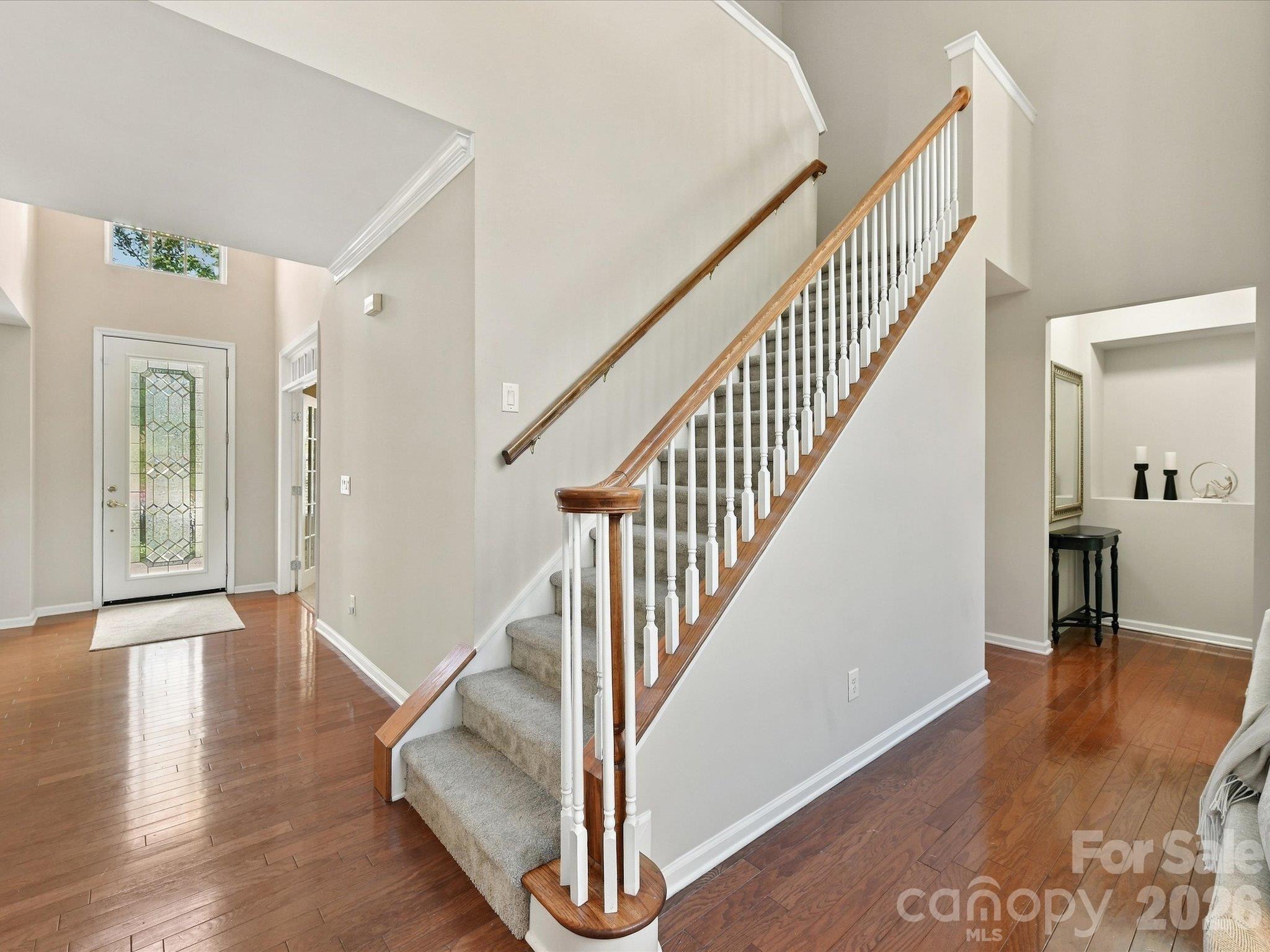 Elegant staircase with classic wood railings overlooks the open living space, creating a seamless flow between levels and enhancing the home's airy feel. - 1788 Oakmont Drive, Denver