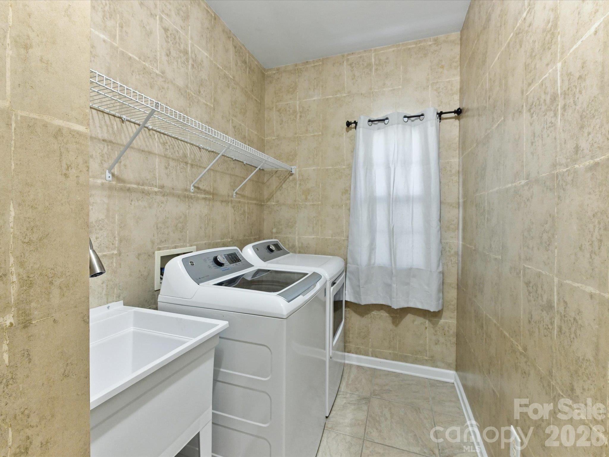 Oversized laundry room with utility sink, built-in shelving, and plenty of storage space to keep everyday tasks organized and convenient. - 1788 Oakmont Drive, Denver