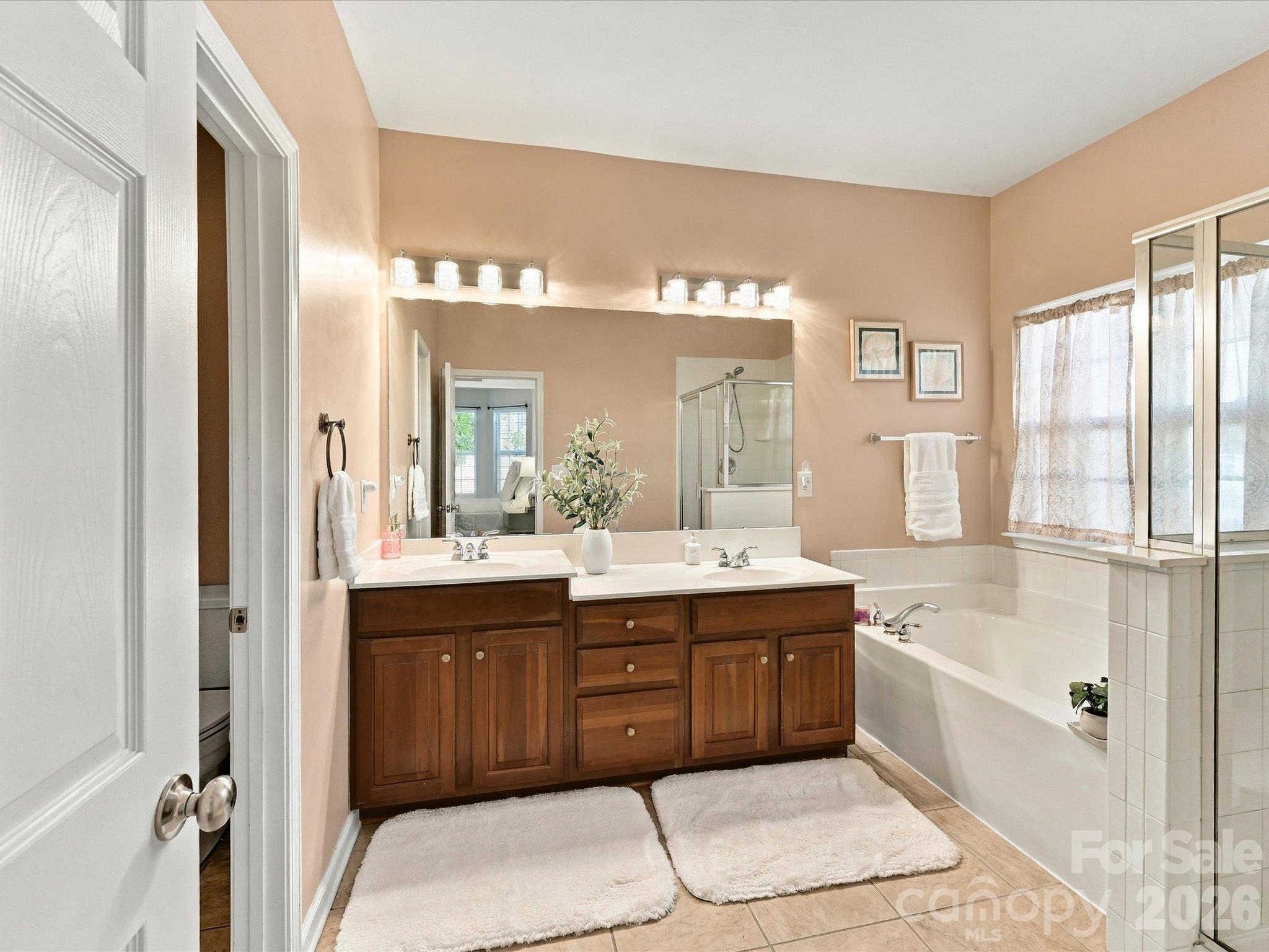 Spa-like primary bathroom featuring a dual-sink vanity, relaxing garden tub, separate glass-enclosed shower, and ample space to start and end your day in comfort. - 1788 Oakmont Drive, Denver