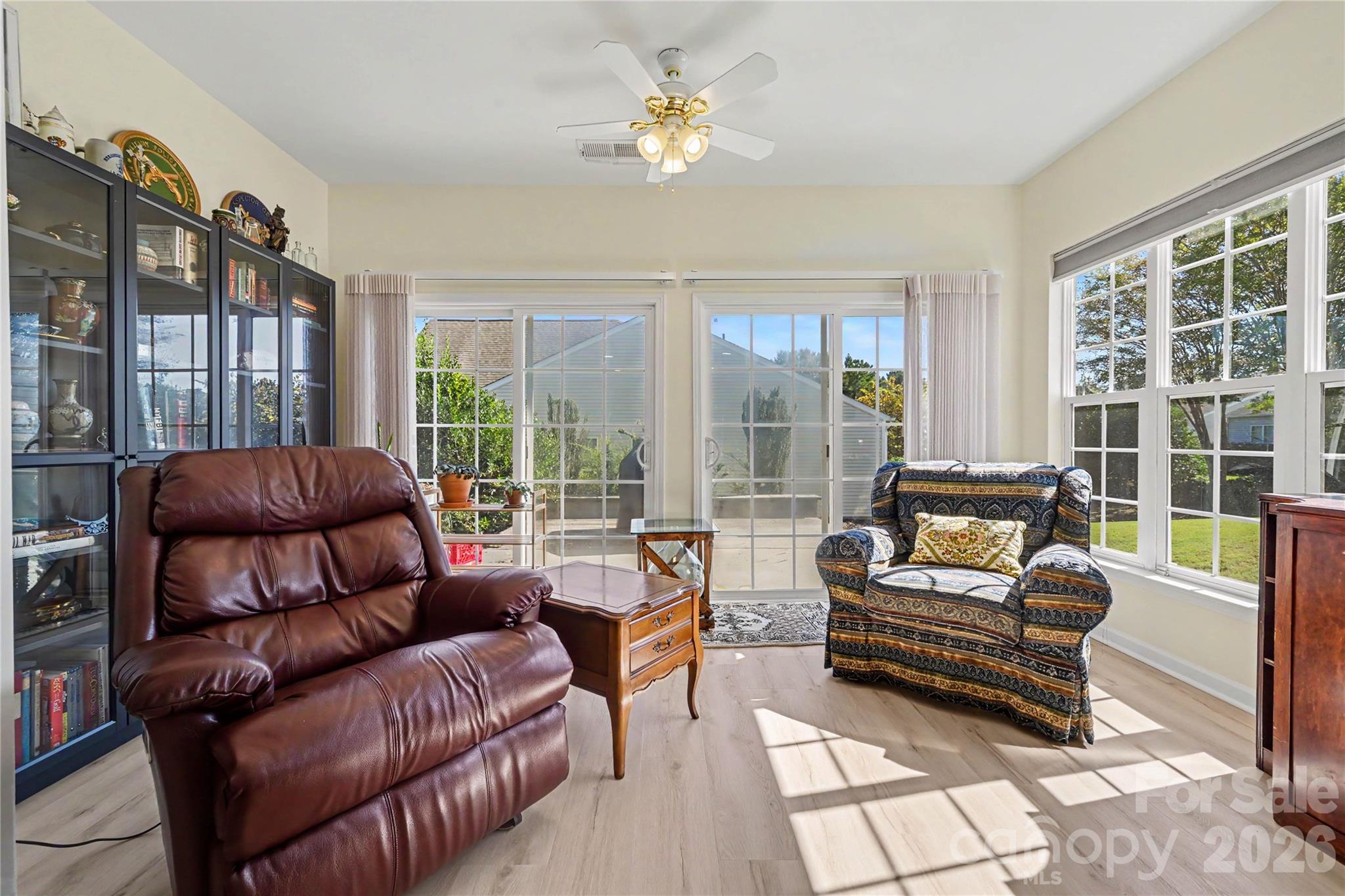 Sunroom features DUAL sliding glass doors, ceiling fan, bright views, and NEW LVP flooring. - 3054 Azalea Drive, Indian Land