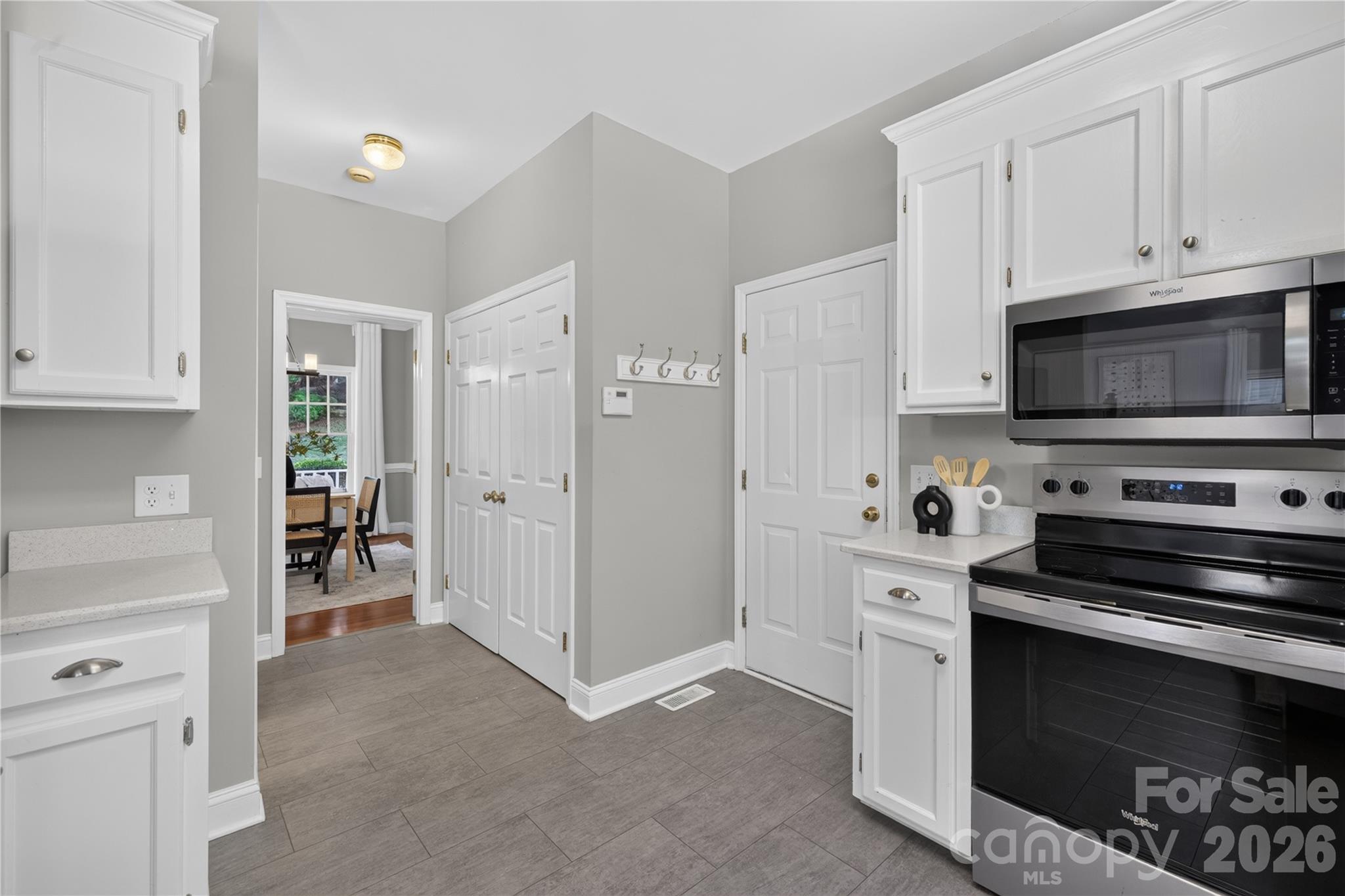 Kitchen with stainless steel appliances and quartz countertops leading to formal dining room. - 4711 Beech Crest Place, Charlotte