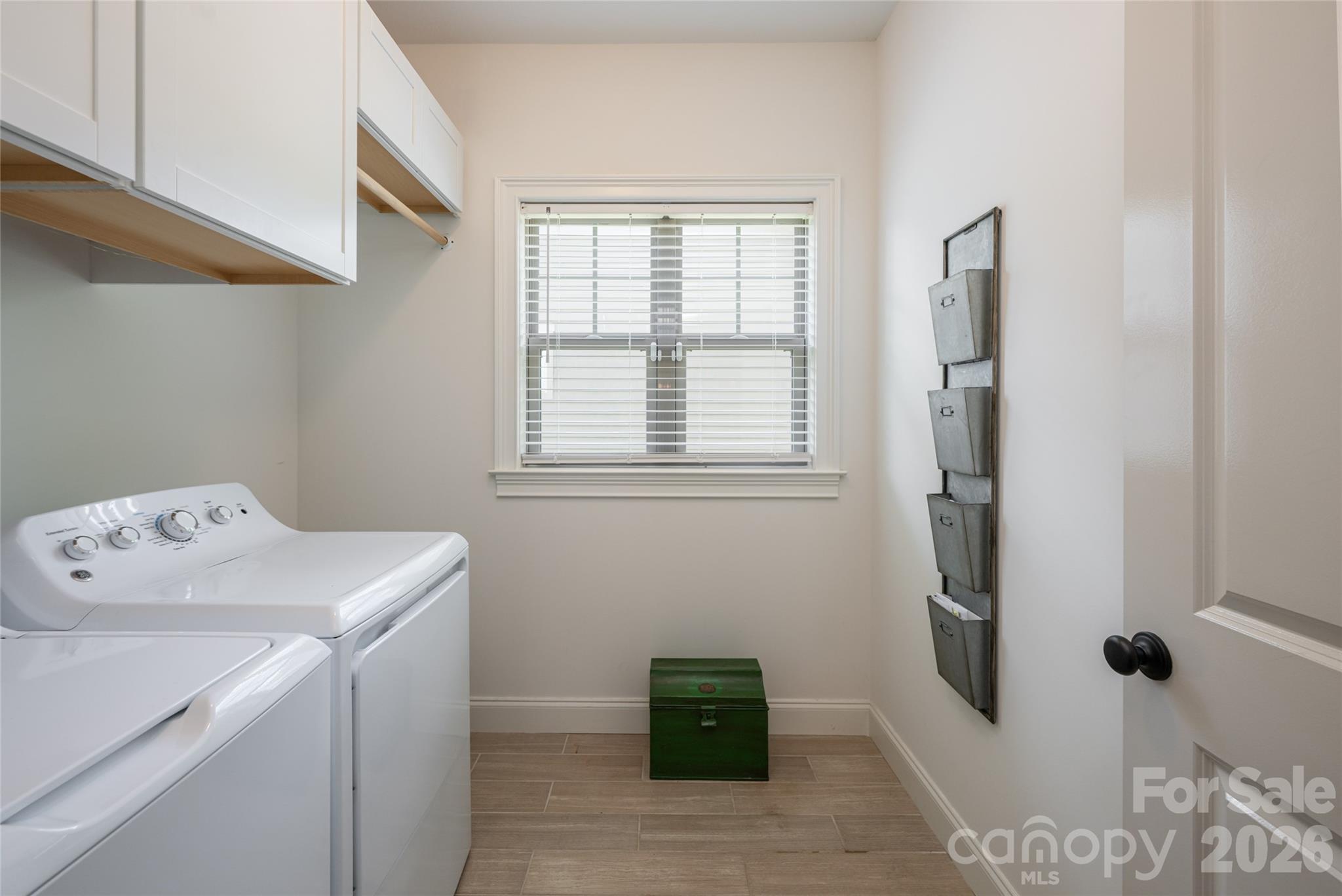 Main-level laundry room with washer, dryer, storage, and natural light. - 17 Asher Lane, Arden