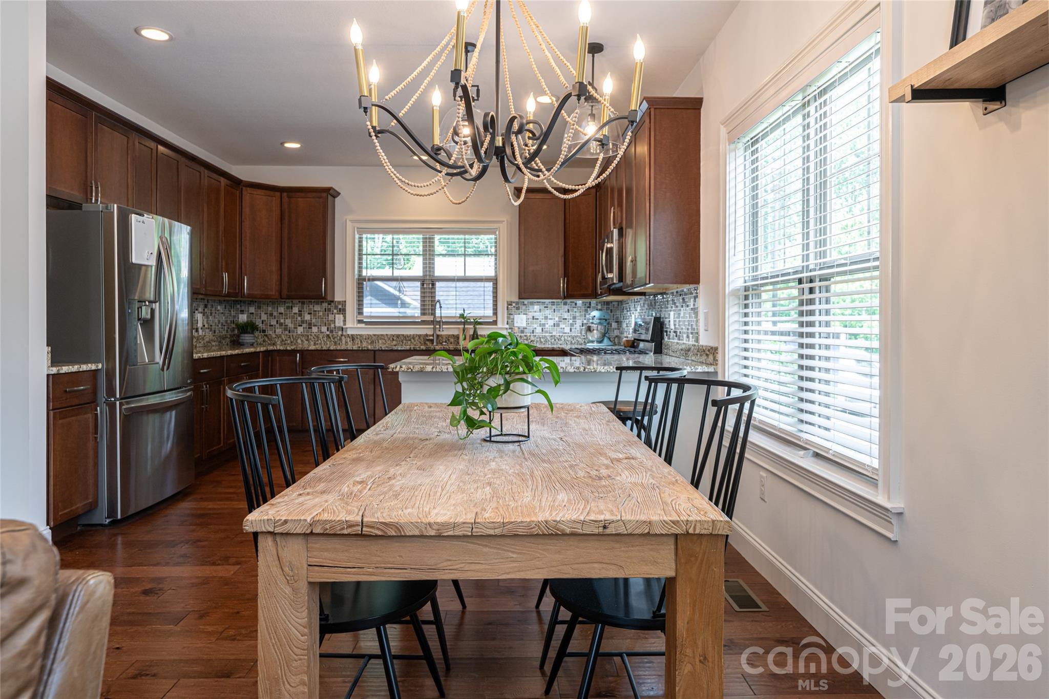 Granite kitchen island with breakfast bar seating beneath an iron chandelier. - 17 Asher Lane, Arden