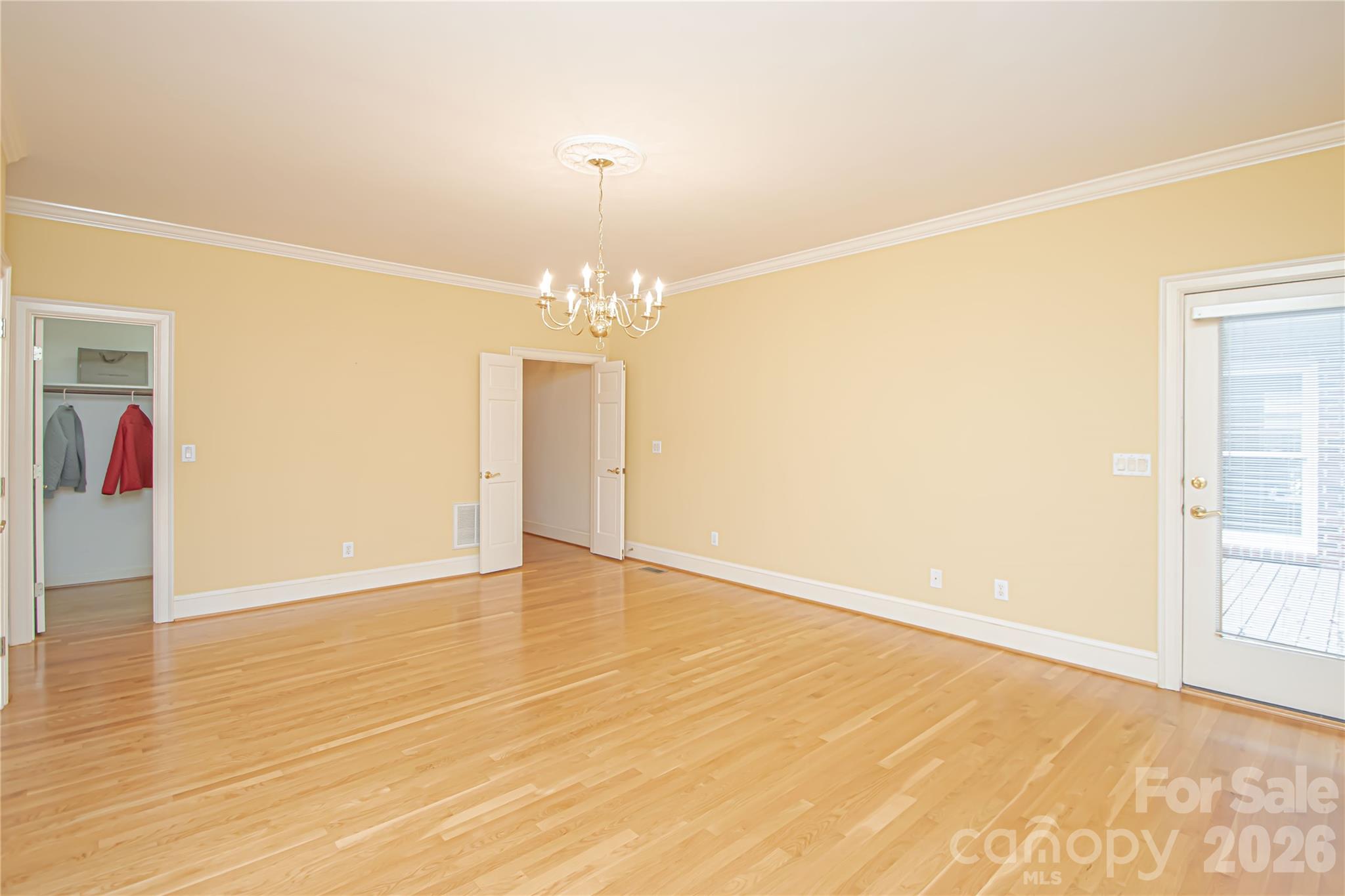 PRIMARY BEDROOM: chandelier with medallion base also pre wired for ceiling fan. This is the view from the sitting corner, walk in closet as well as the double French doors. Primary Bath and two linear closets are to the left. New Smoke Detector 9/26. - 5480 Glen Forest Drive, Charlotte