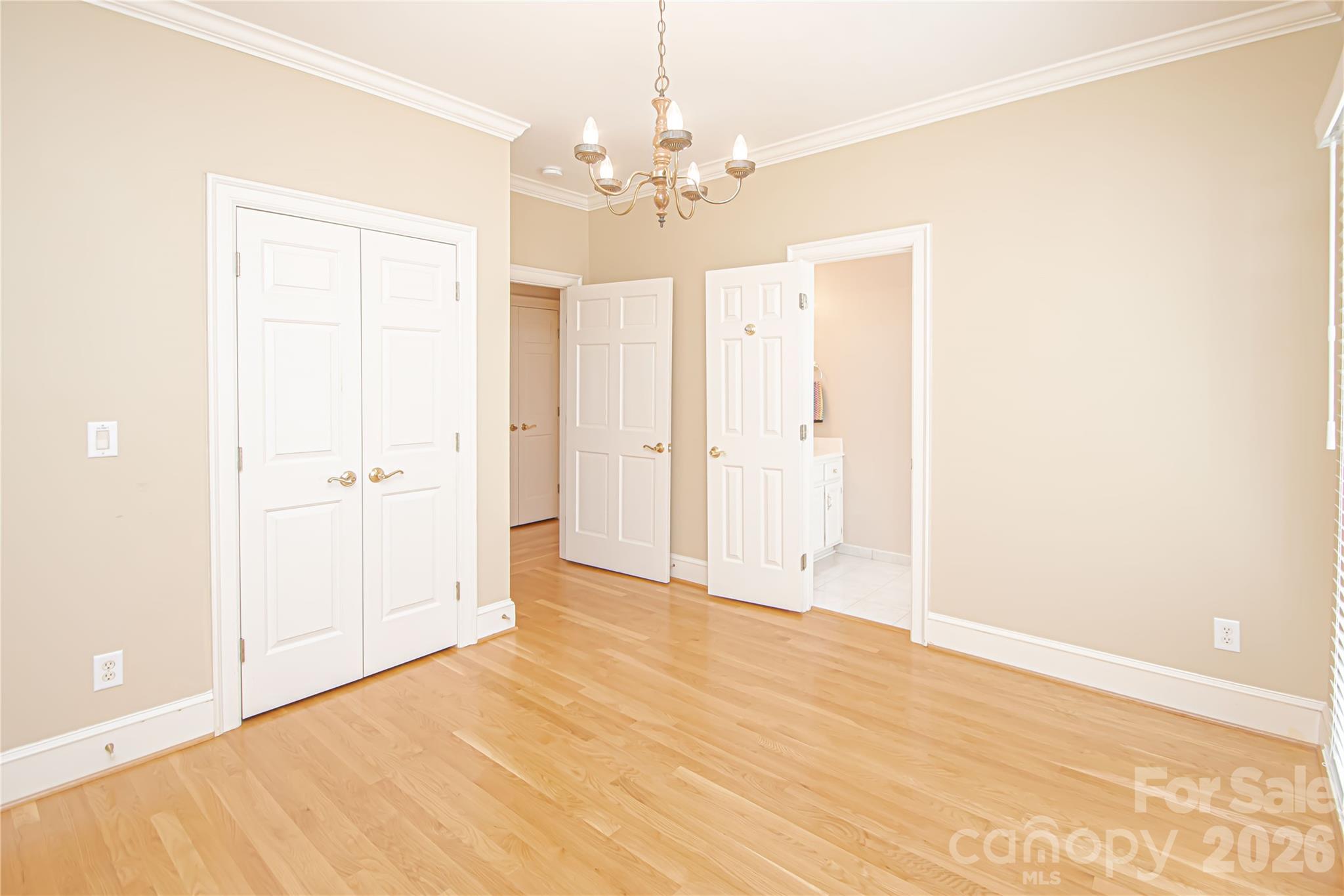 FRONT BEDROOM 12'x13': new blinds, crown molding and chandelier with medallion base. New Smoke Detector 9/26. A light filled bedroom by its non pictured floor to ceiling windows. Deep linear closet to the left. Right door is access to toilet and sink with a Shared shower/tub. - 5480 Glen Forest Drive, Charlotte