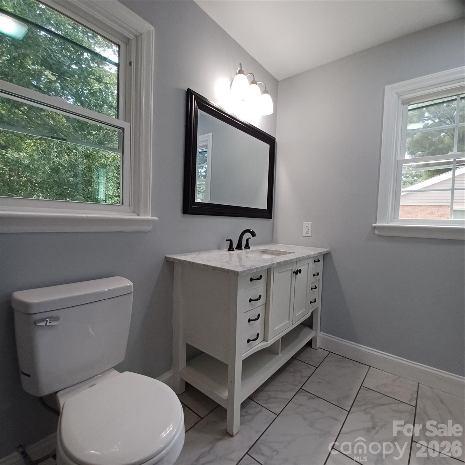 Primary Bath with updated sink base cabinet, flooring, mirrow, and lighting - 5717 Ruth Drive, Charlotte