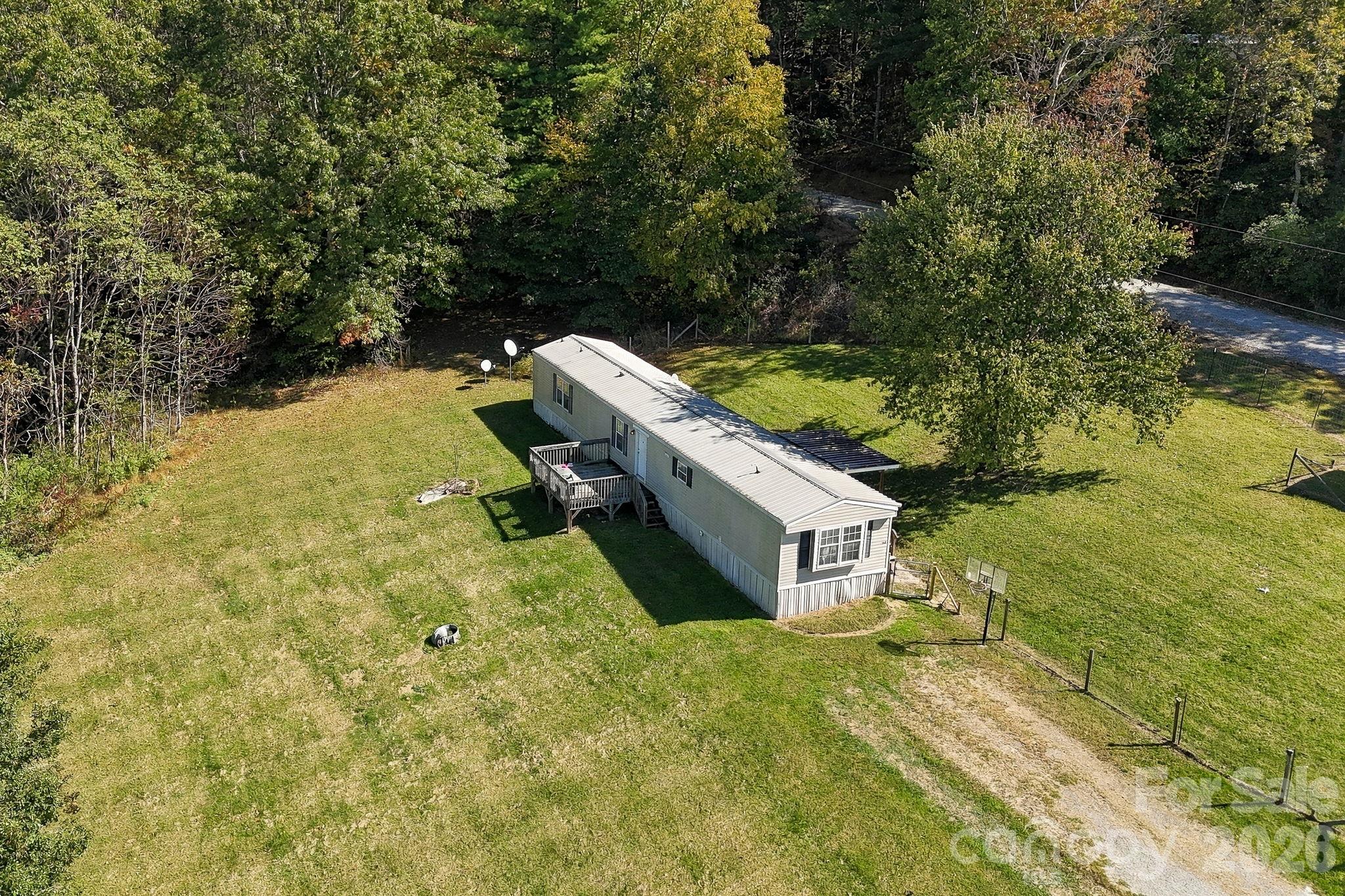 Aerial view showcasing the generous yard space, established driveway access, and peaceful wooded setting. - 631 Union Hill Road, Hendersonville