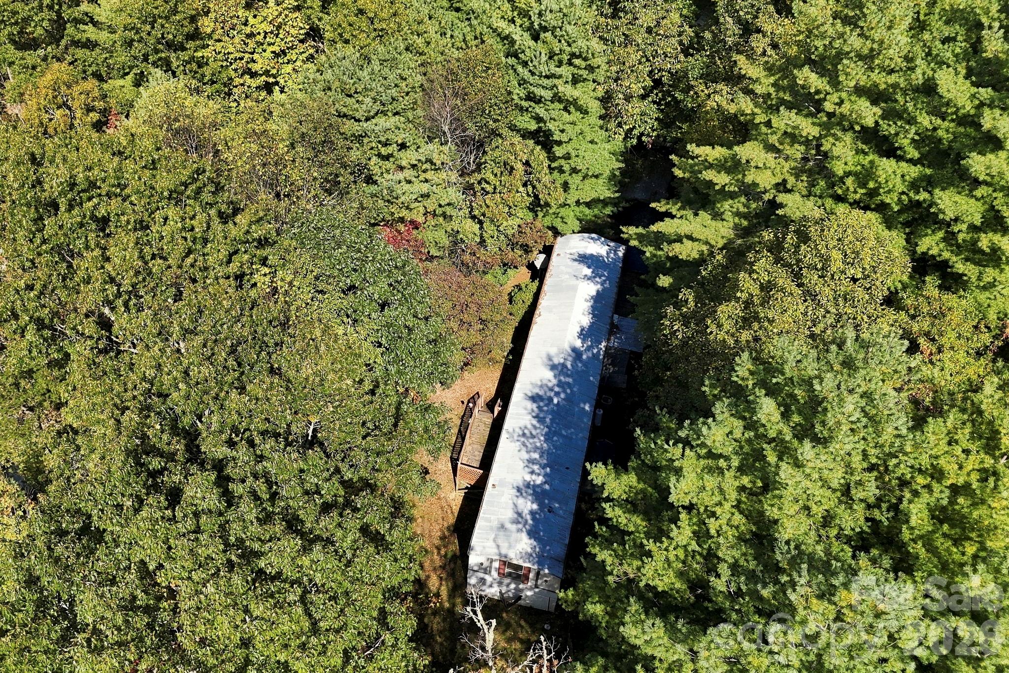 Mobile home nestled among mature trees, showcasing the natural privacy and established residential use of the property. - 631 Union Hill Road, Hendersonville