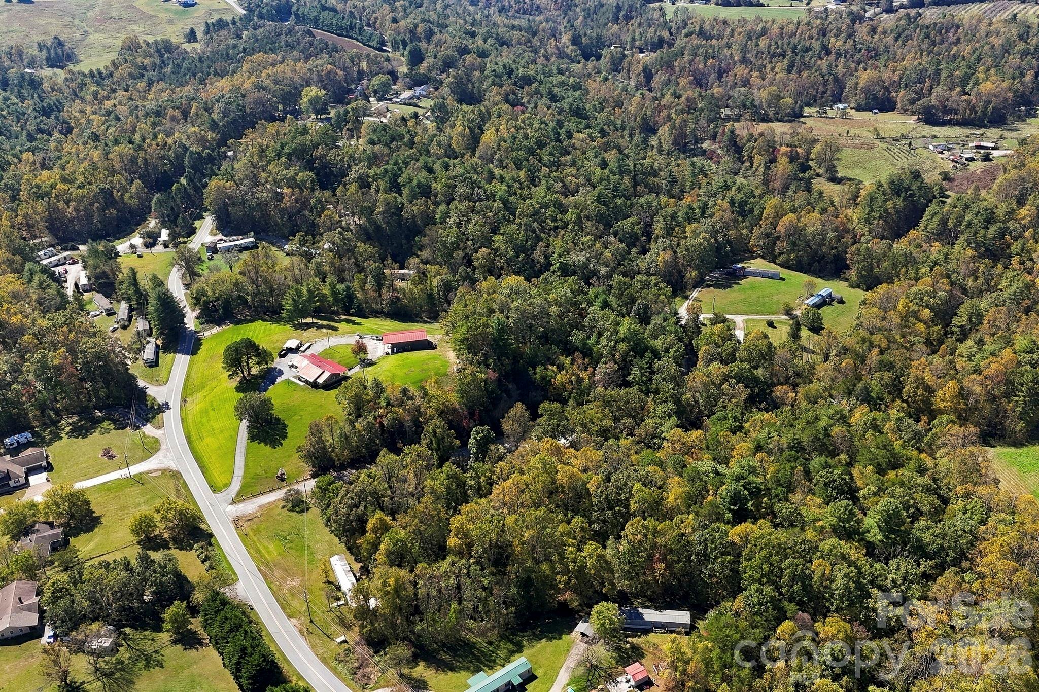 Sweeping aerial perspective highlights the property's wooded surroundings, rural setting, and proximity to an established state-maintained road. - 631 Union Hill Road, Hendersonville