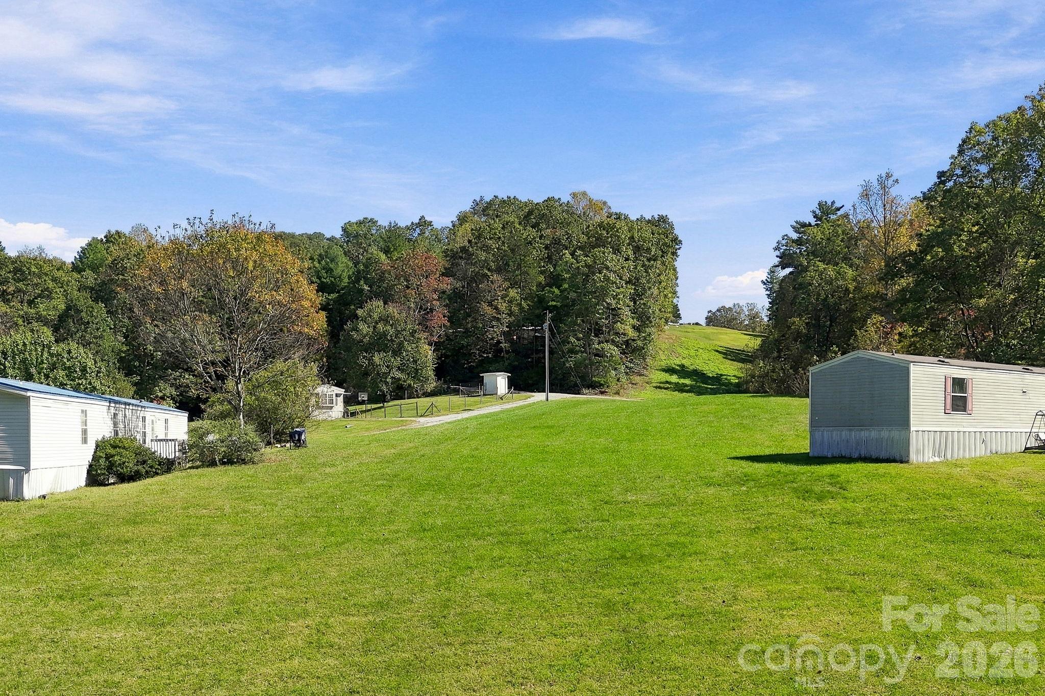 Expansive grassy clearing between existing residences highlights the property's exceptionally usable terrain and spacious setting. - 631 Union Hill Road, Hendersonville