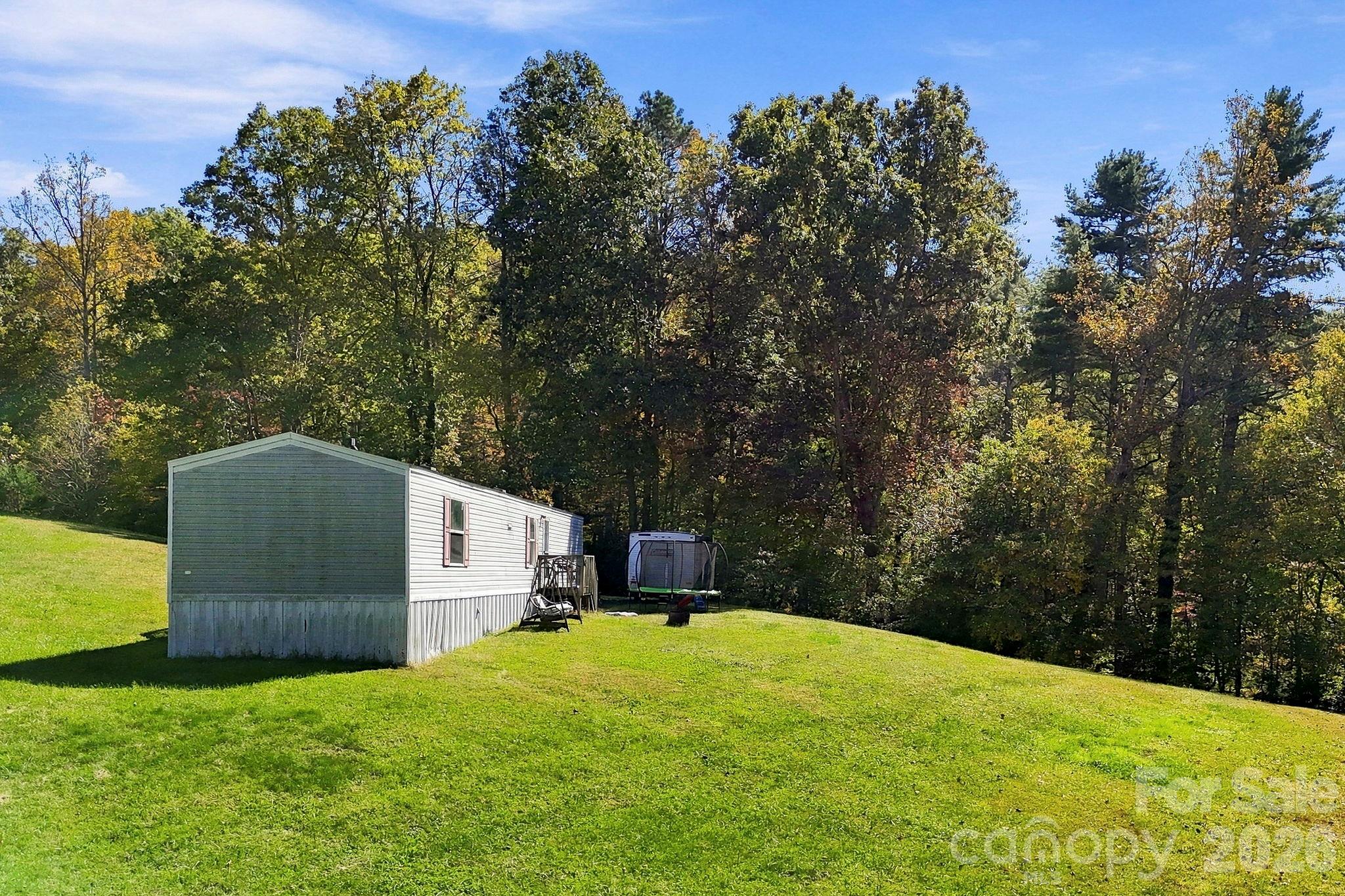 Established residential site featuring a spacious lawn and mature hardwoods along the property's wooded edge. - 631 Union Hill Road, Hendersonville