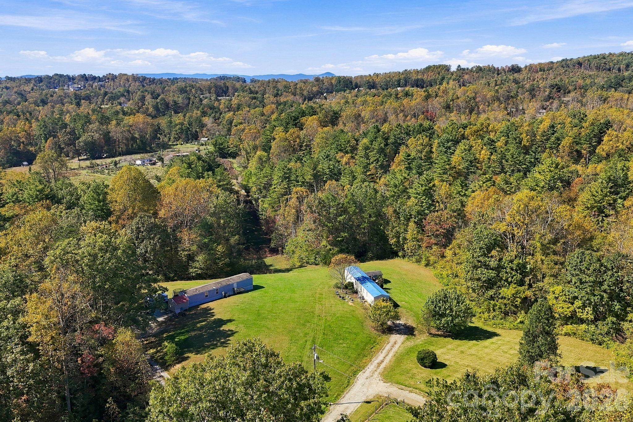 Beautiful aerial perspective captures open lawns, colorful hardwoods, and distant mountain scenery across the surrounding countryside. - 631 Union Hill Road, Hendersonville