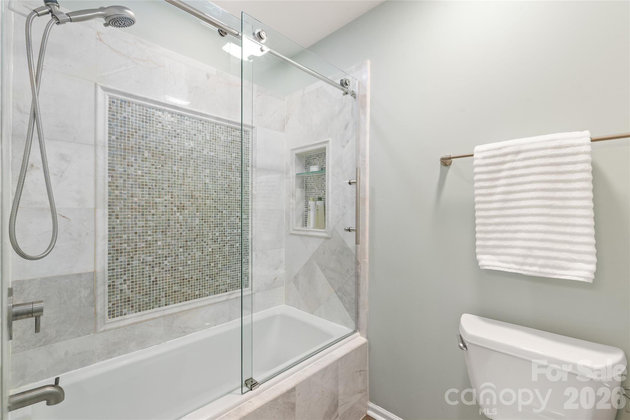 The updated Jack and Jill bathroom features crisp tile flooring, quartz countertops, high-efficiency toilets, and custom stone-tile details—perfectly blending shared convenience with luxury style. - 4780 Grier Farm Lane, Charlotte