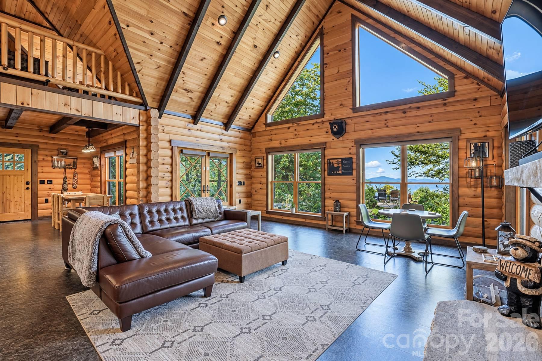 Great room with walls of windows and leather sectional - 18 Fairway Run, Bryson City