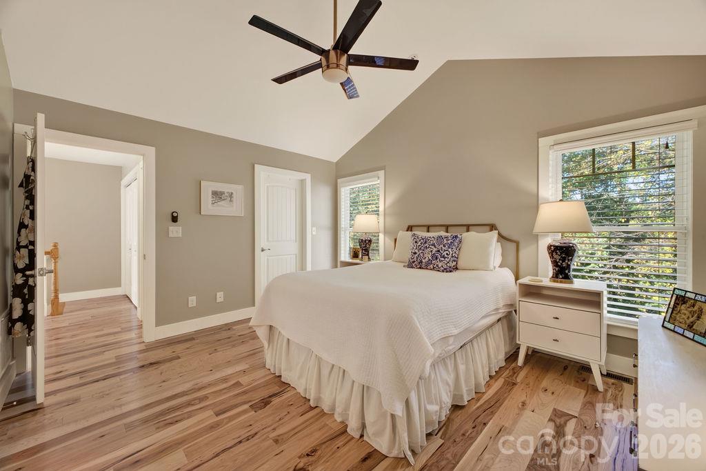 A lovely primary bedroom with cathedral ceilings and windows that look over the fenced back yard... - 98 Langwell Avenue, Asheville