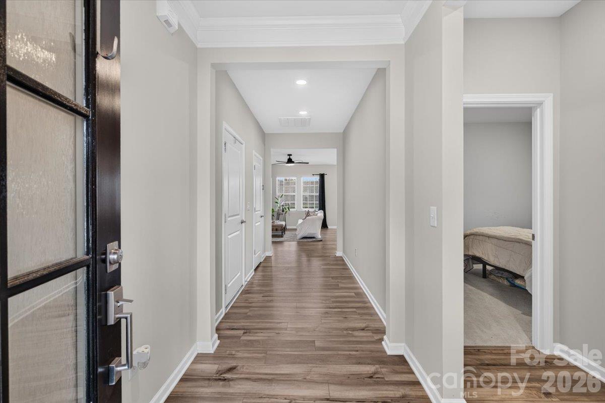 Bright and welcoming hallway featuring gorgeous continuous flooring and modern dark-framed glass doors. - 155 White Apple Way, Statesville