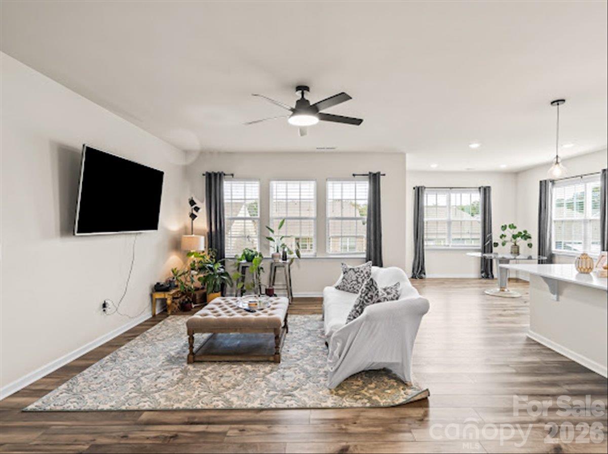 Sun-drenched living room offering plenty of natural light, a ceiling fan, and abundant space for relaxing or entertaining. - 155 White Apple Way, Statesville