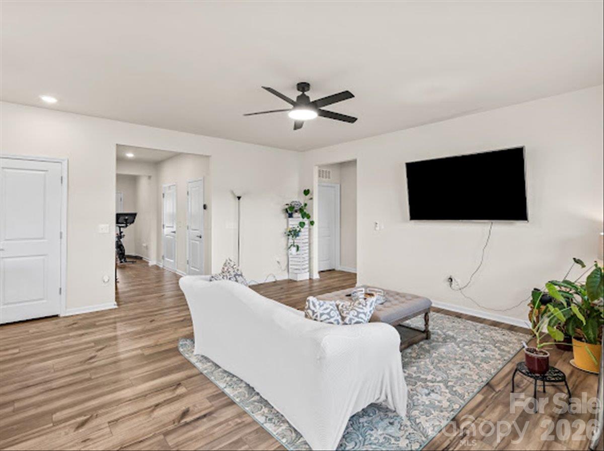Inviting living area featuring a modern ceiling fan, stylish layout, and seamless flow into the kitchen. - 155 White Apple Way, Statesville