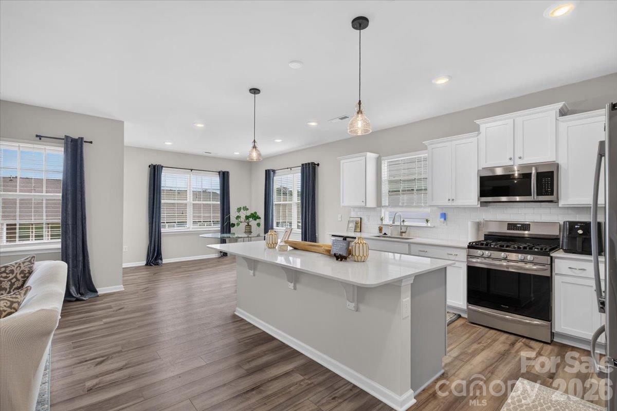Perfect open-concept layout showcasing the flow from the expansive kitchen island directly into the bright, airy living space. - 155 White Apple Way, Statesville