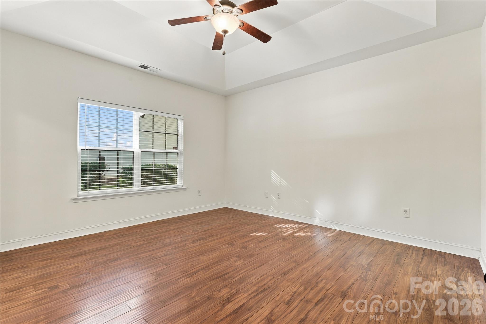 The primary suite has wood-look floors, a ceiling fan, and plenty of natural light. - 327 Annaberg Lane, Monroe