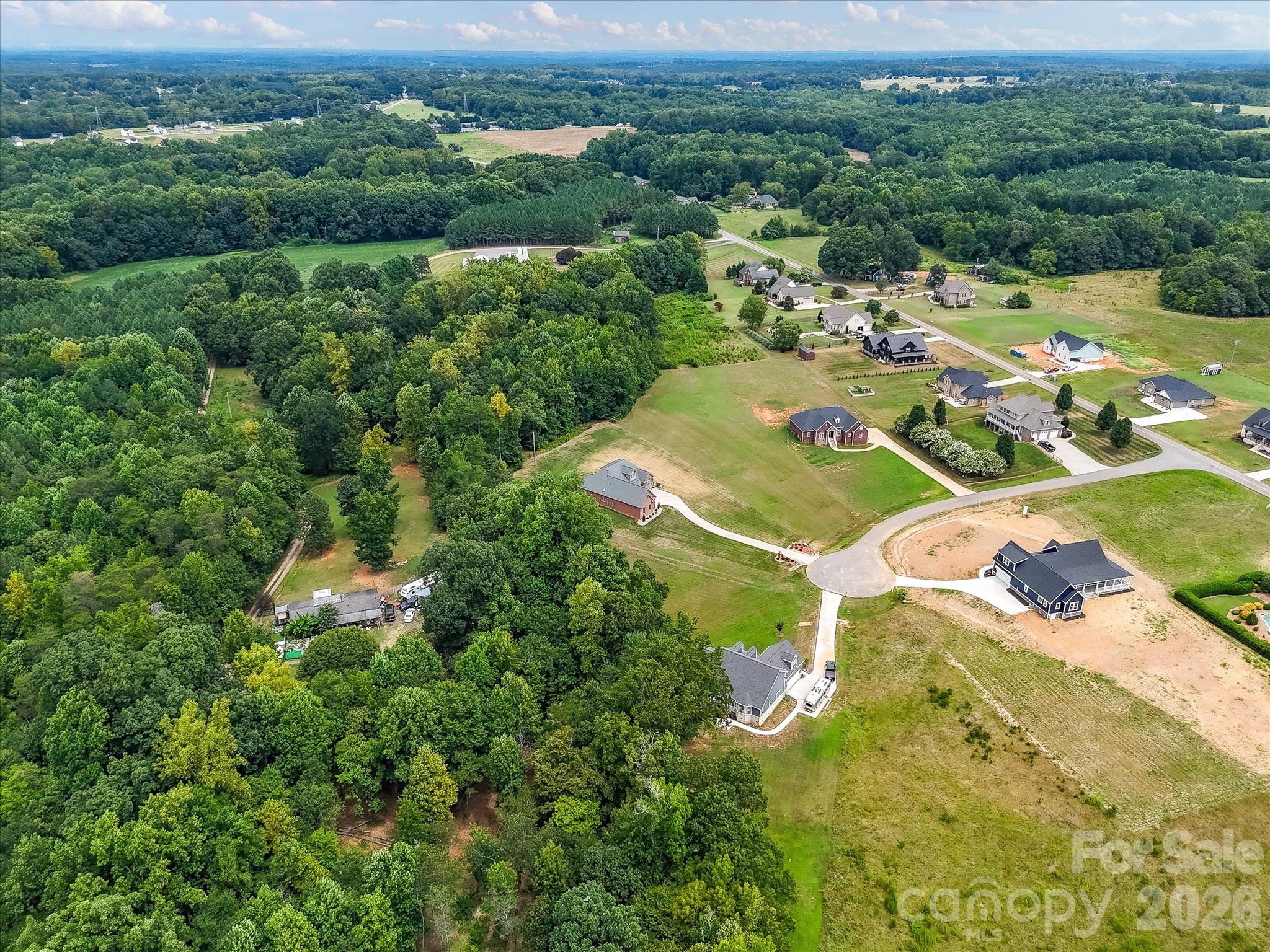 Expansive aerial view showcasing a peaceful cul-de-sac community with spacious homesites, beautiful custom homes, and lush wooded surroundings offering privacy and picturesque countryside scenery. - Lot 15 Peacehaven Place, Statesville