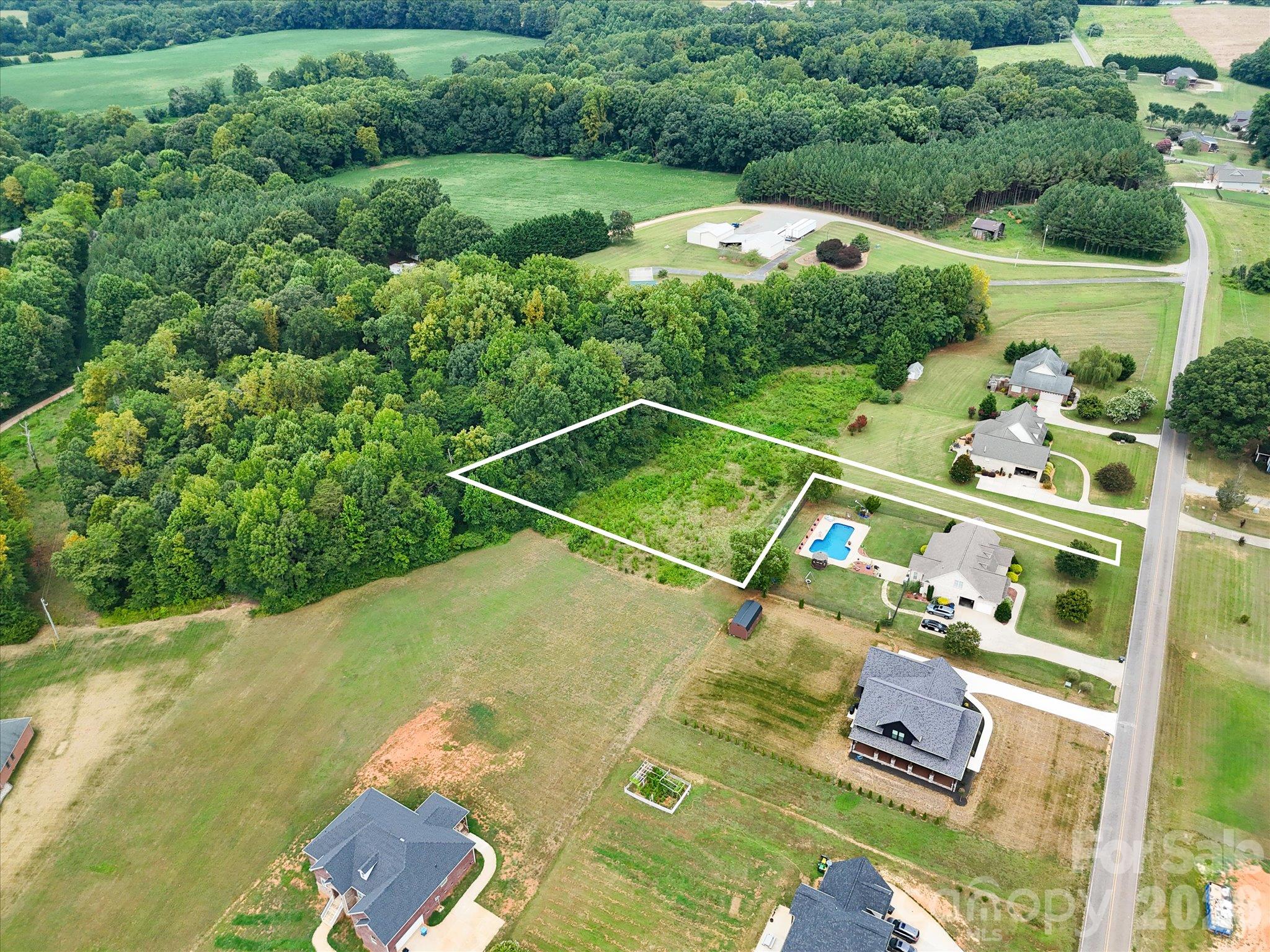 Aerial view highlighting the outlined homesite with a spacious, partially wooded landscape, mature trees, and a peaceful residential setting surrounded by beautiful custom homes and expansive green spaces. - 494 New Salem Road, Statesville