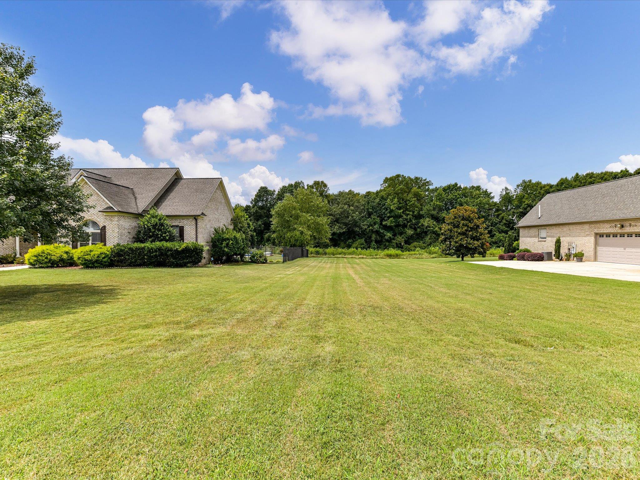 Expansive, level grassy homesite nestled between beautiful brick residences, offering a peaceful setting with mature trees, open green space, and a picturesque backdrop for your future dream home. - 494 New Salem Road, Statesville
