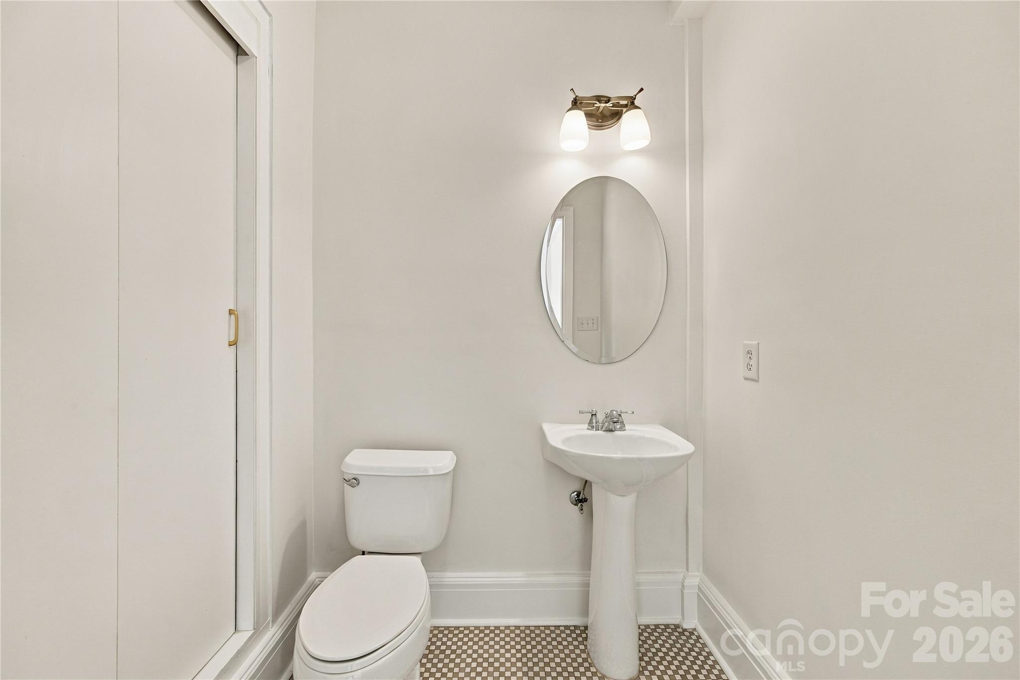 Charming half bath with original checkerboard tile in warm earth tones and convenient closet storage. - 712 Louise Avenue, Charlotte