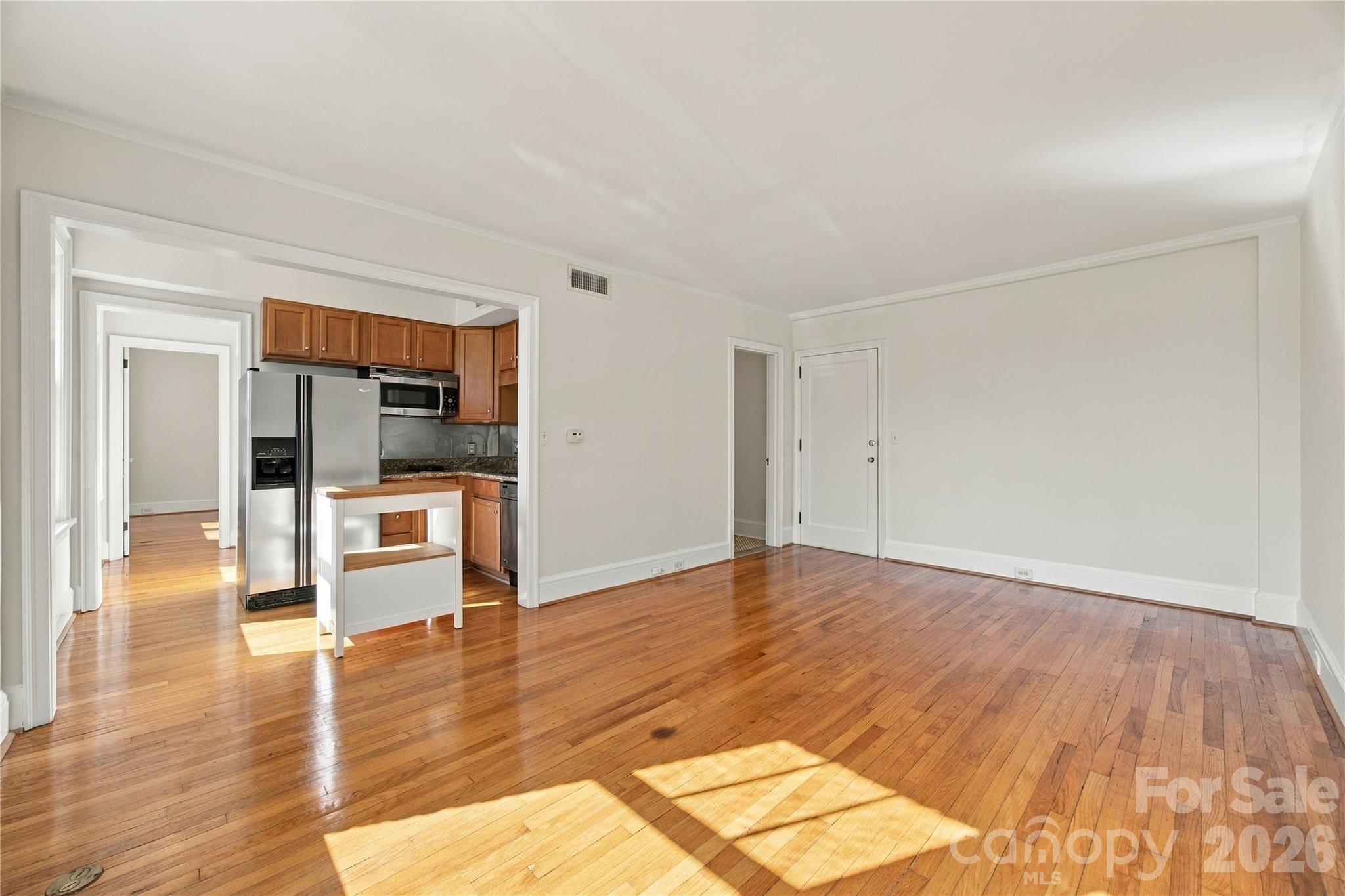 Sunlight floods the living room, with views into the kitchen and down the hall toward the utility room and bedroom. - 712 Louise Avenue, Charlotte