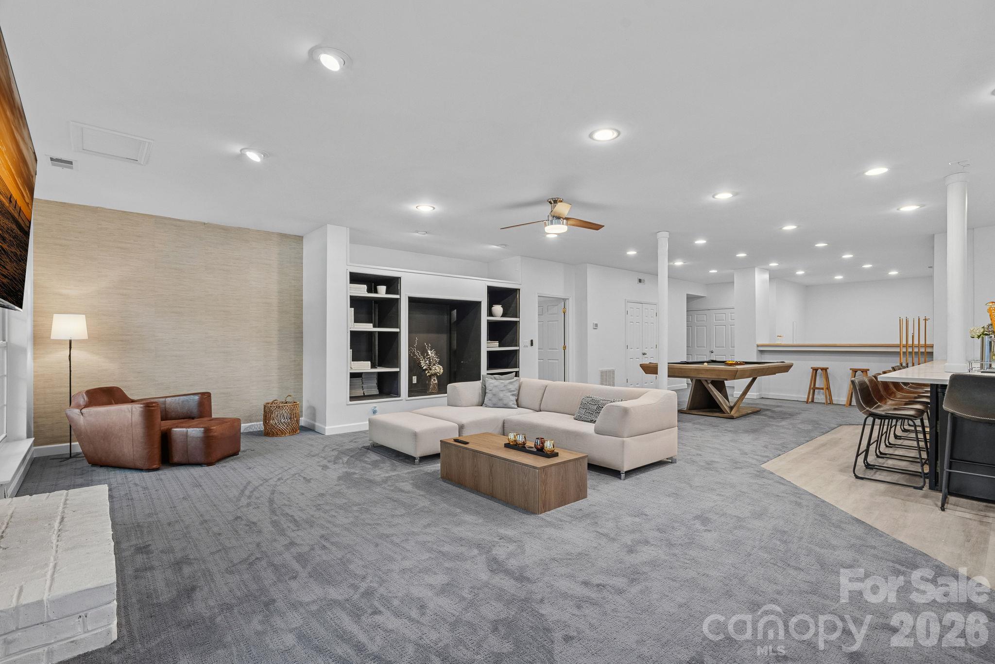 Basement living area with gas fireplace and built ins, also an extra flex space beyond the pool table - 148 Sunrise Circle, Mooresville