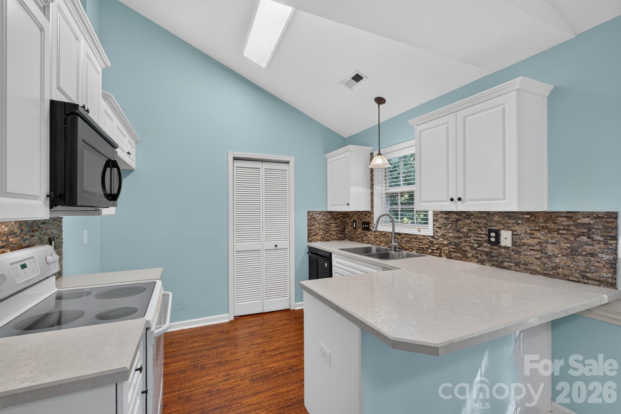 Functional kitchen complete with crisp white cabinetry, dark countertops, and a breakfast bar pass-through. - 702 Painted Lady Court, Rock Hill