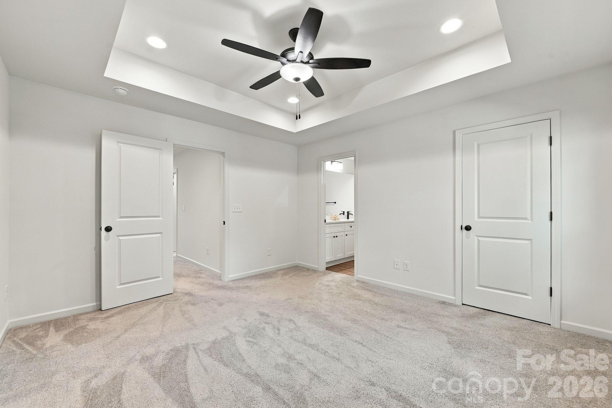 Primary bedroom with tray ceiling overlooks tree-lined yard for privacy - 4715 Crestmont Drive, Charlotte