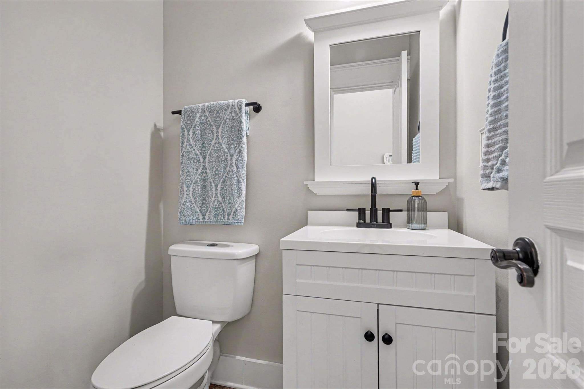 Half Bathroom located on the main level. Fresh, neutral paint. White cabinet and mirror add a sleek look to this beautiful space. - 3585 Leighton Drive SW, Concord