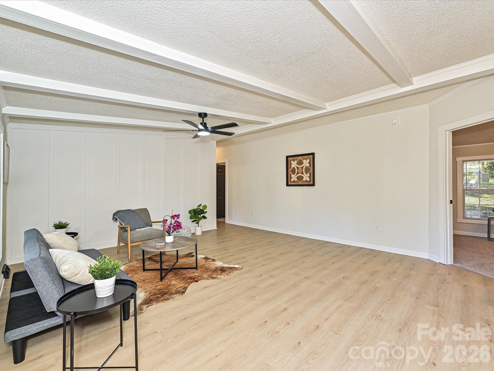 View from entering the home. Board and batten accent wall on left hand side, exposed decorative beams on ceiling. New luxury vinyl plank flooring adorn the space. - 1711 Trexlar Avenue, Gastonia