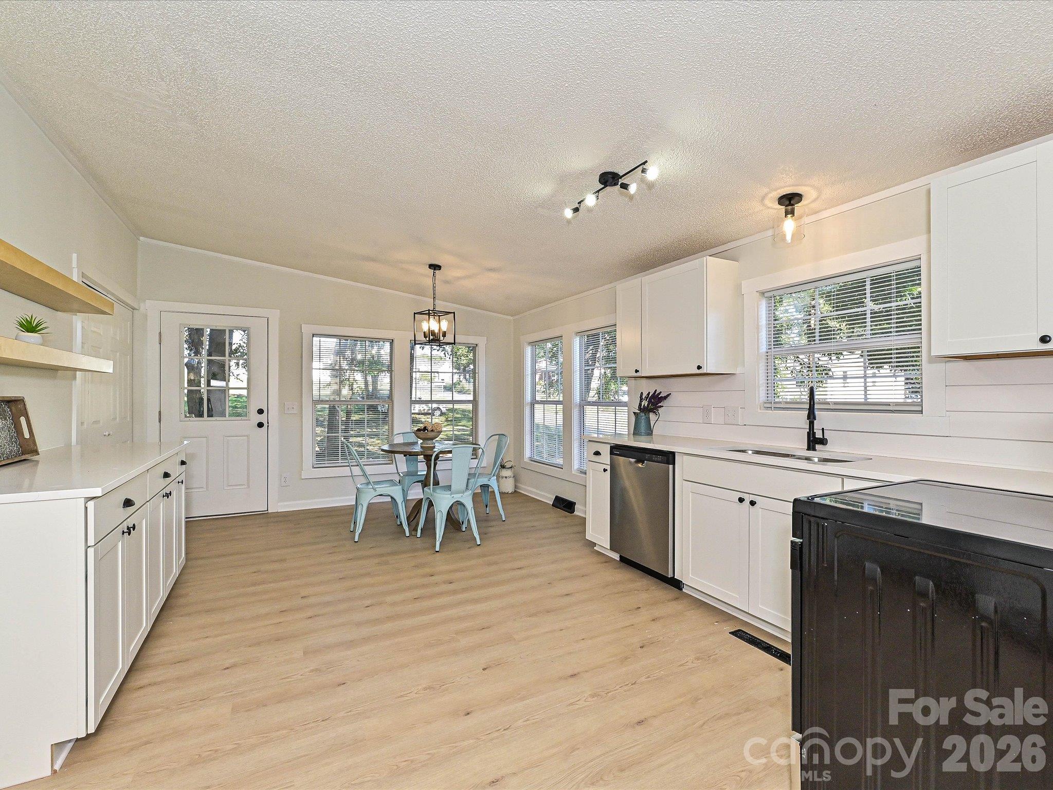 Open kitchen floor plan with new white shaker cabinets, white quarty countertops, custom shelving and more. - 1711 Trexlar Avenue, Gastonia