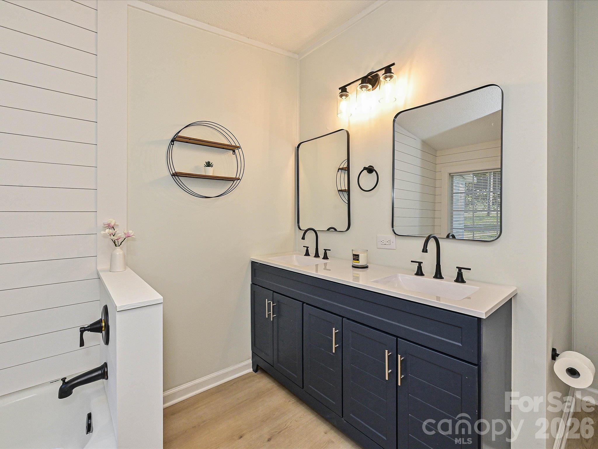 Primary en-suite bathroom view #2 highlighting the new double vanity, matte black plumbing fixtures, farmhouse mirrors and light fixture. - 1711 Trexlar Avenue, Gastonia