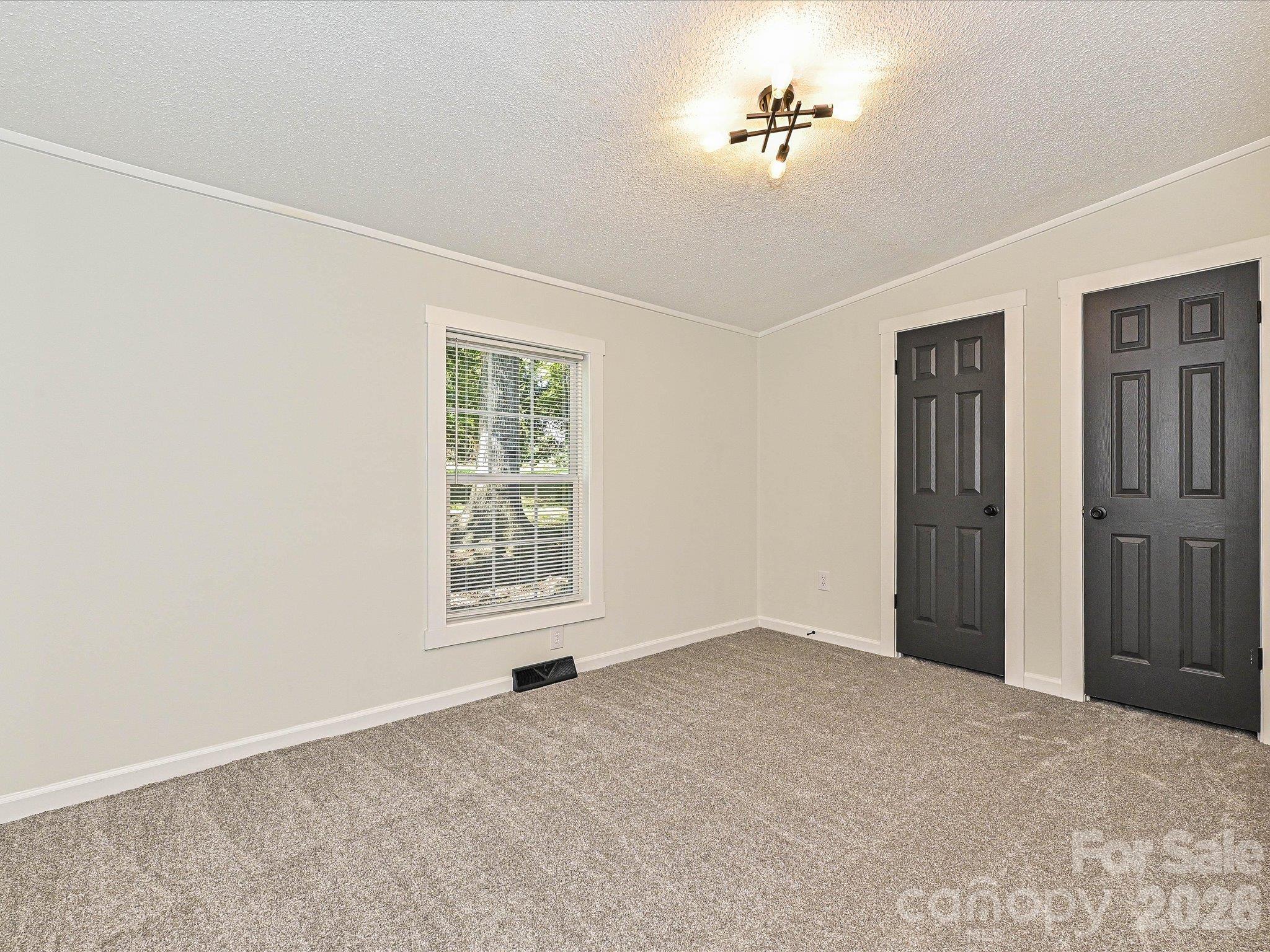 View of bedroom #3 with fresh new carpet, paint, blinds and light fixture. Iron ore accent color on the doors. - 1711 Trexlar Avenue, Gastonia
