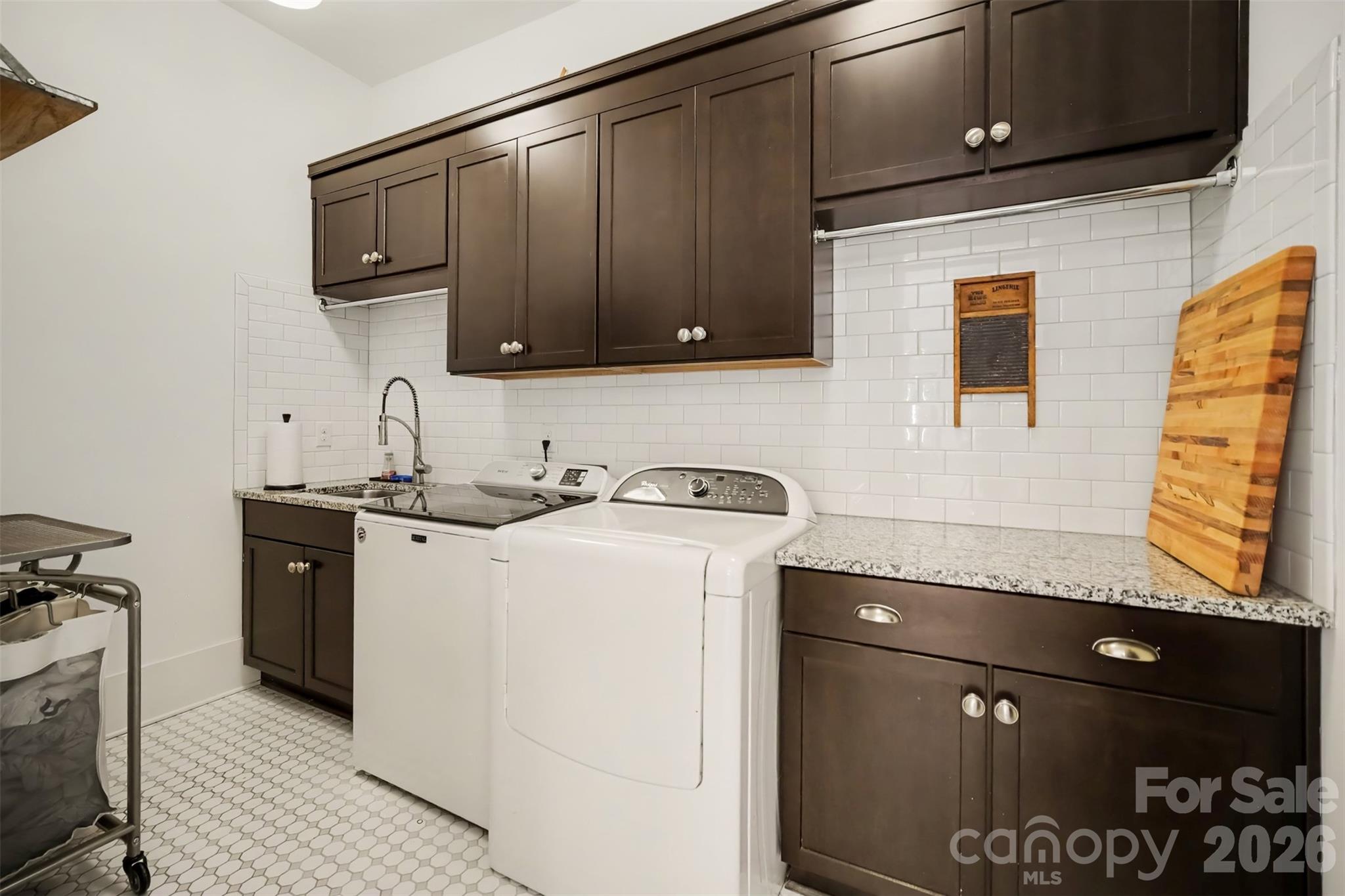 Main level large laundry room with lots of cabinets, counter space & sink. - 206 June Bug Lane, Fort Mill
