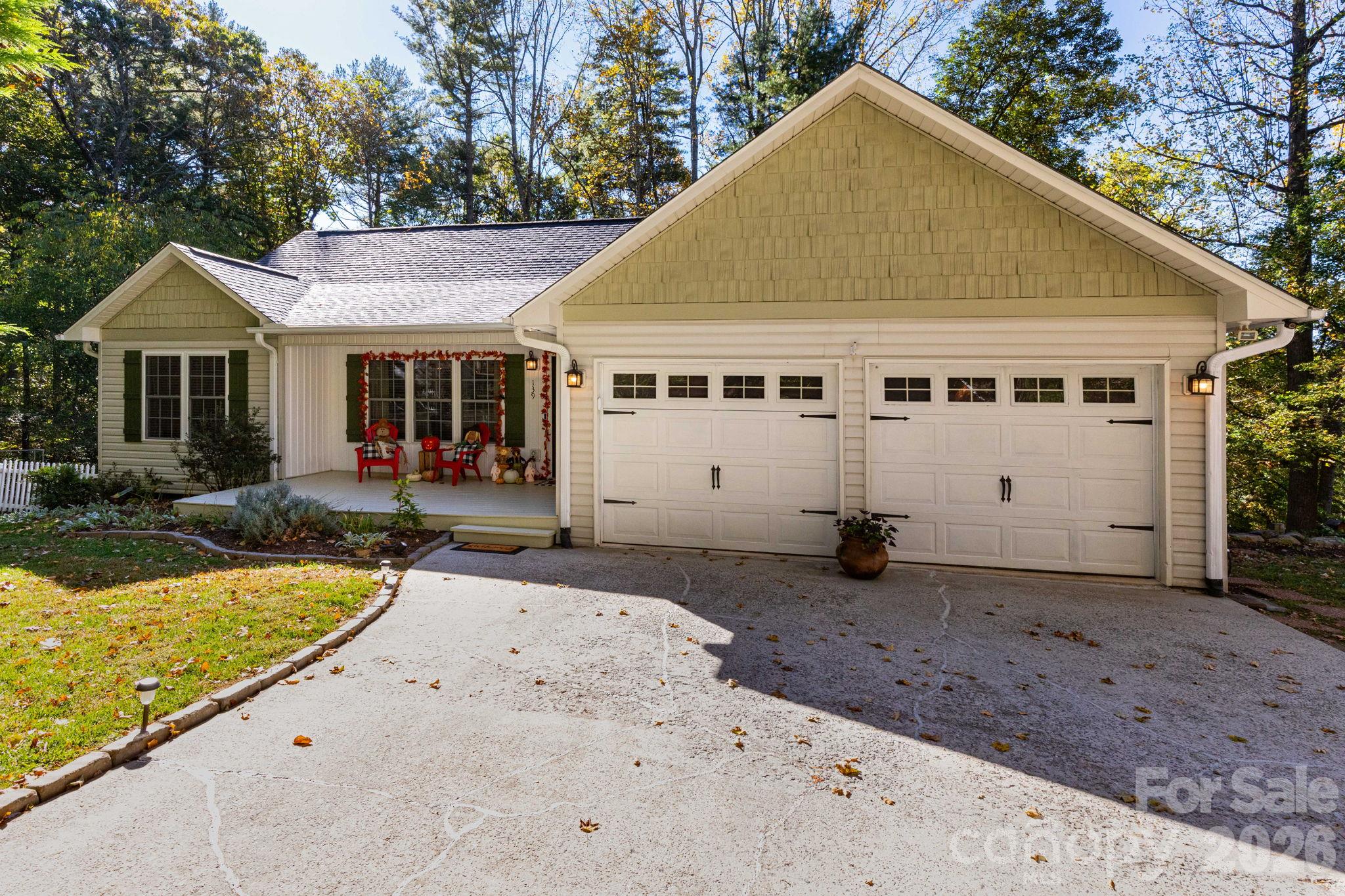 Front exterior highlighting the attached two-car garage, paved driveway, covered entry, and landscaped yard. - 139 Lone Eagle Lane, Hendersonville