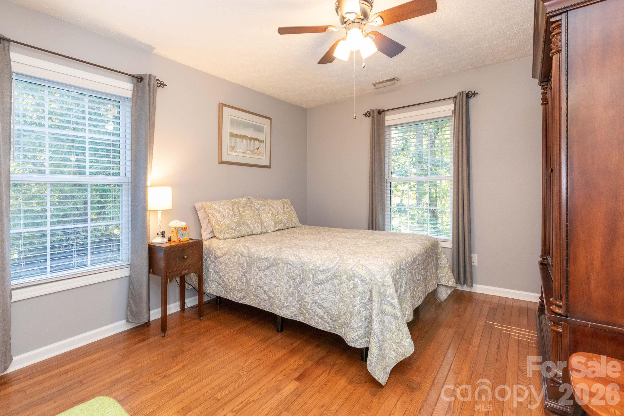 Bright bedroom with windows on two walls, wood flooring, and a ceiling fan for added comfort. - 139 Lone Eagle Lane, Hendersonville