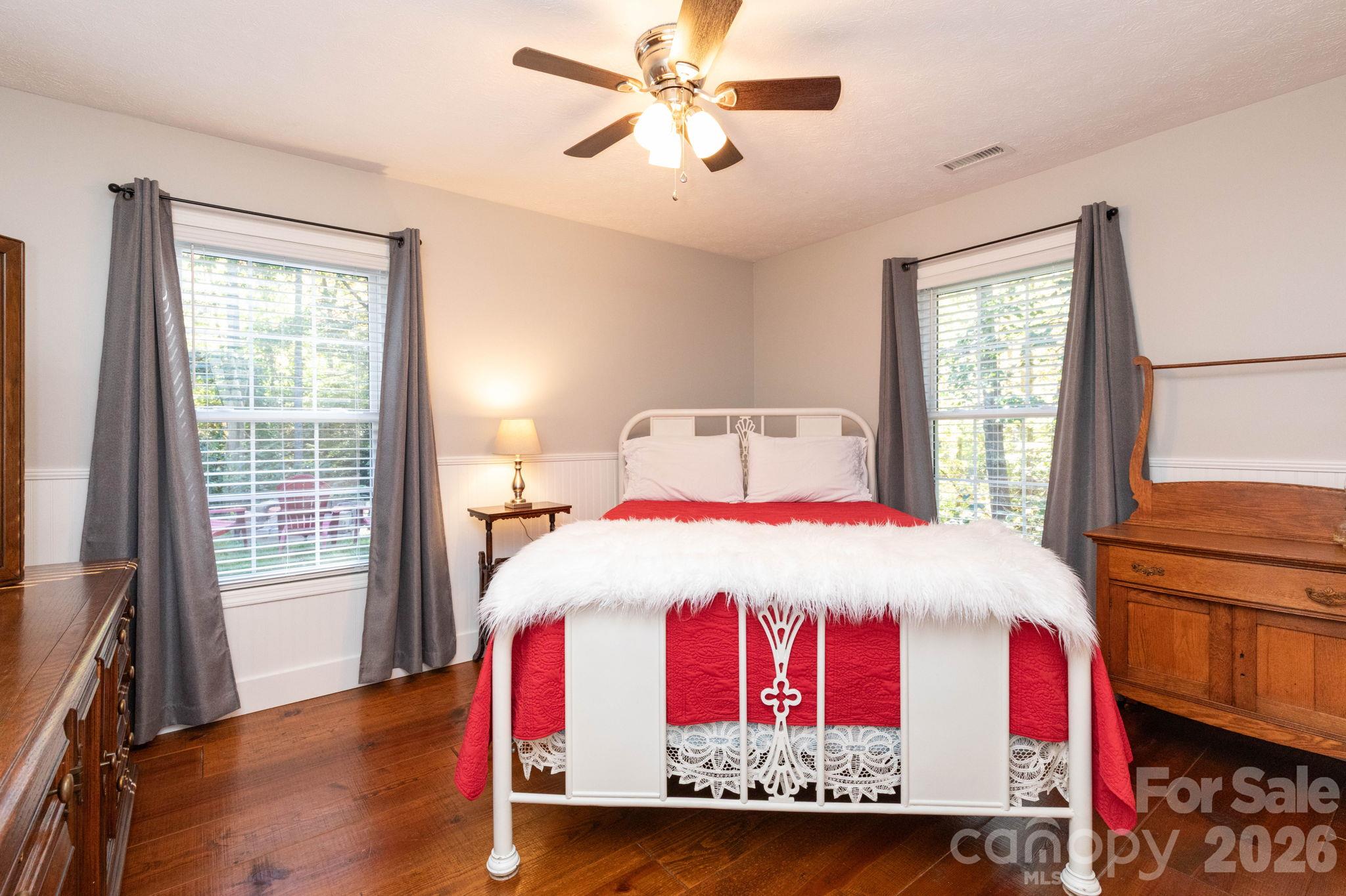 Bright bonus bedroom featuring wood flooring, windows on two walls, and a ceiling fan. - 139 Lone Eagle Lane, Hendersonville